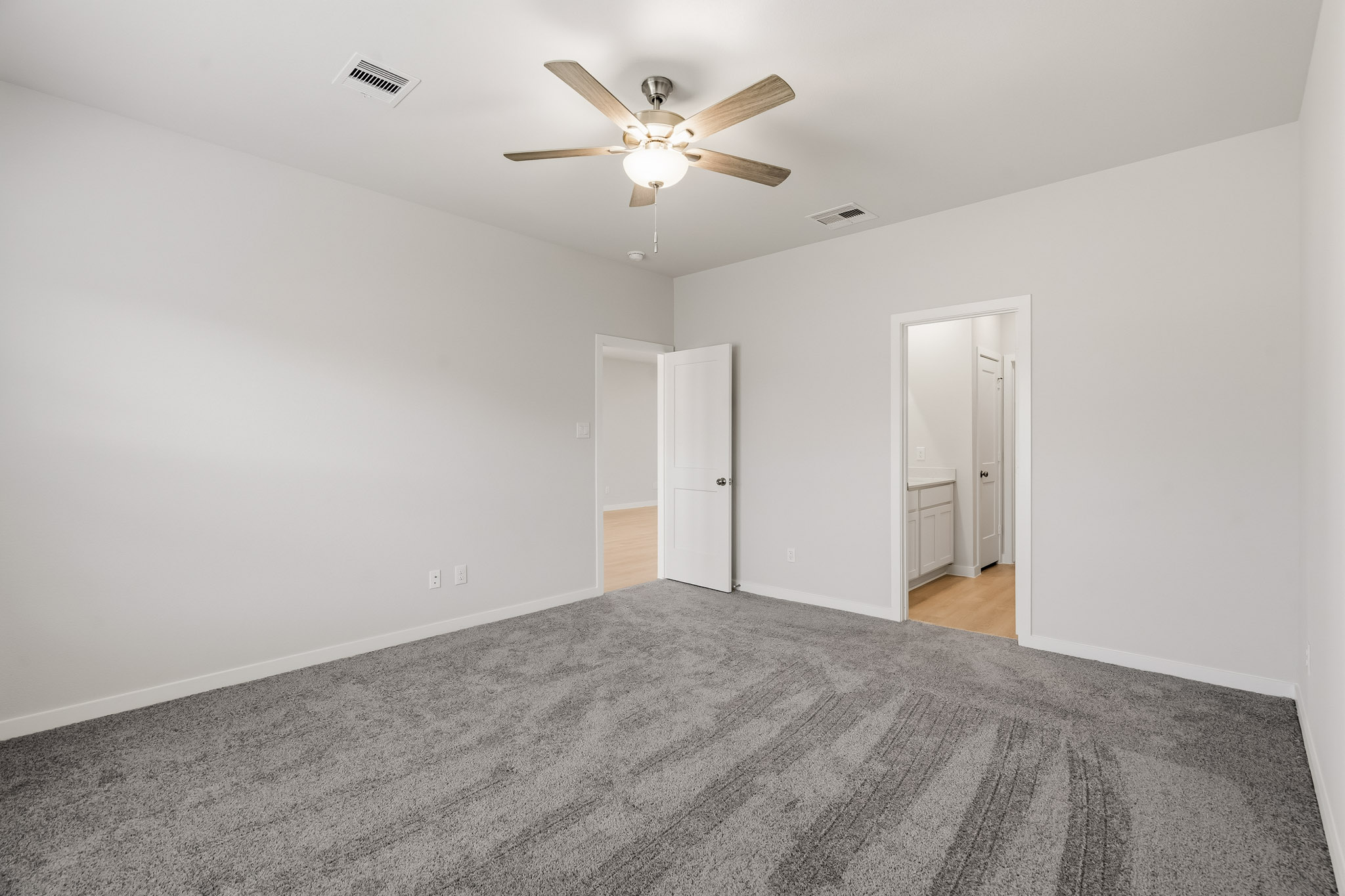 A room with a ceiling fan and a carpet.