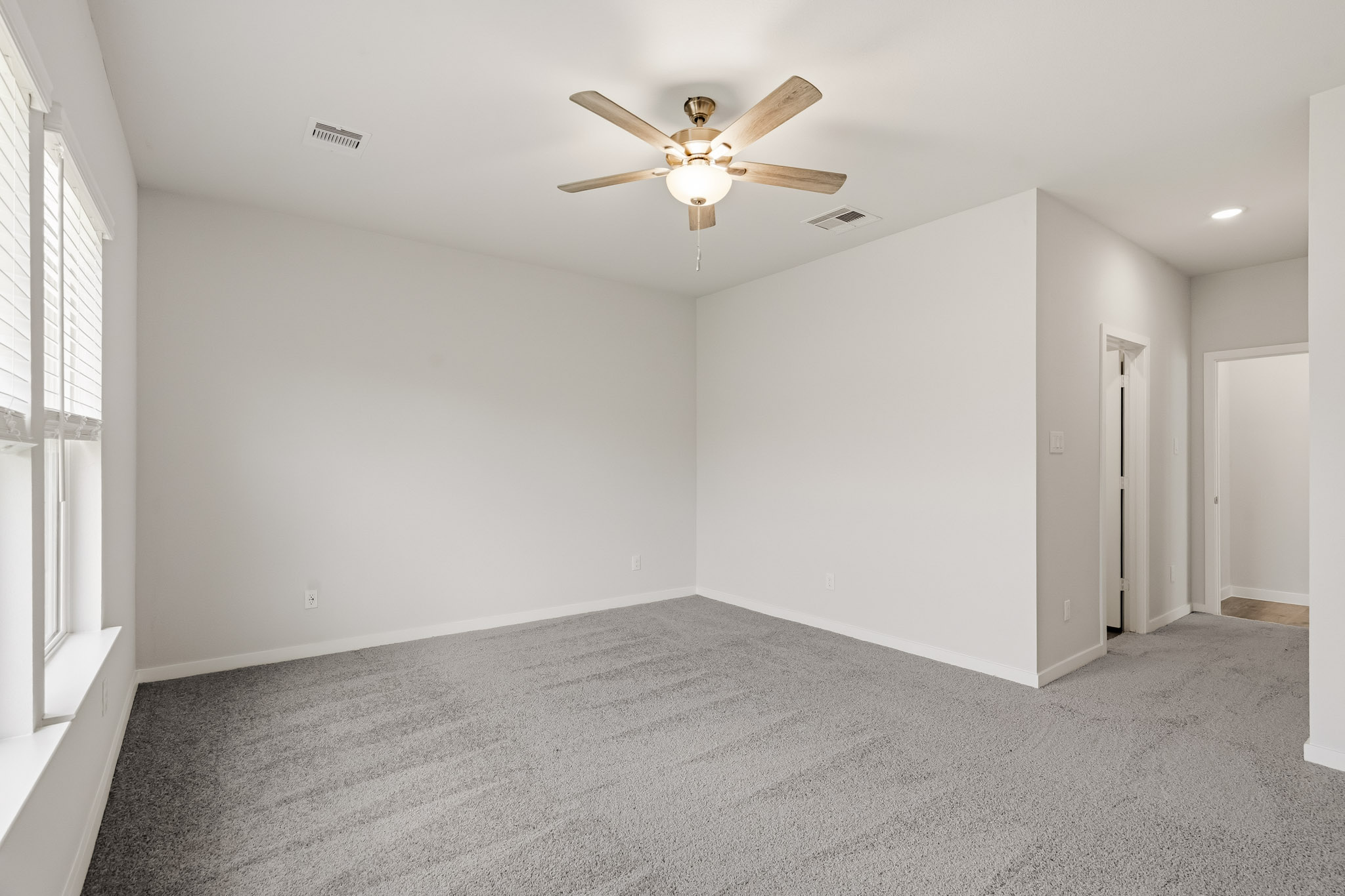 A room with a ceiling fan and a carpet.