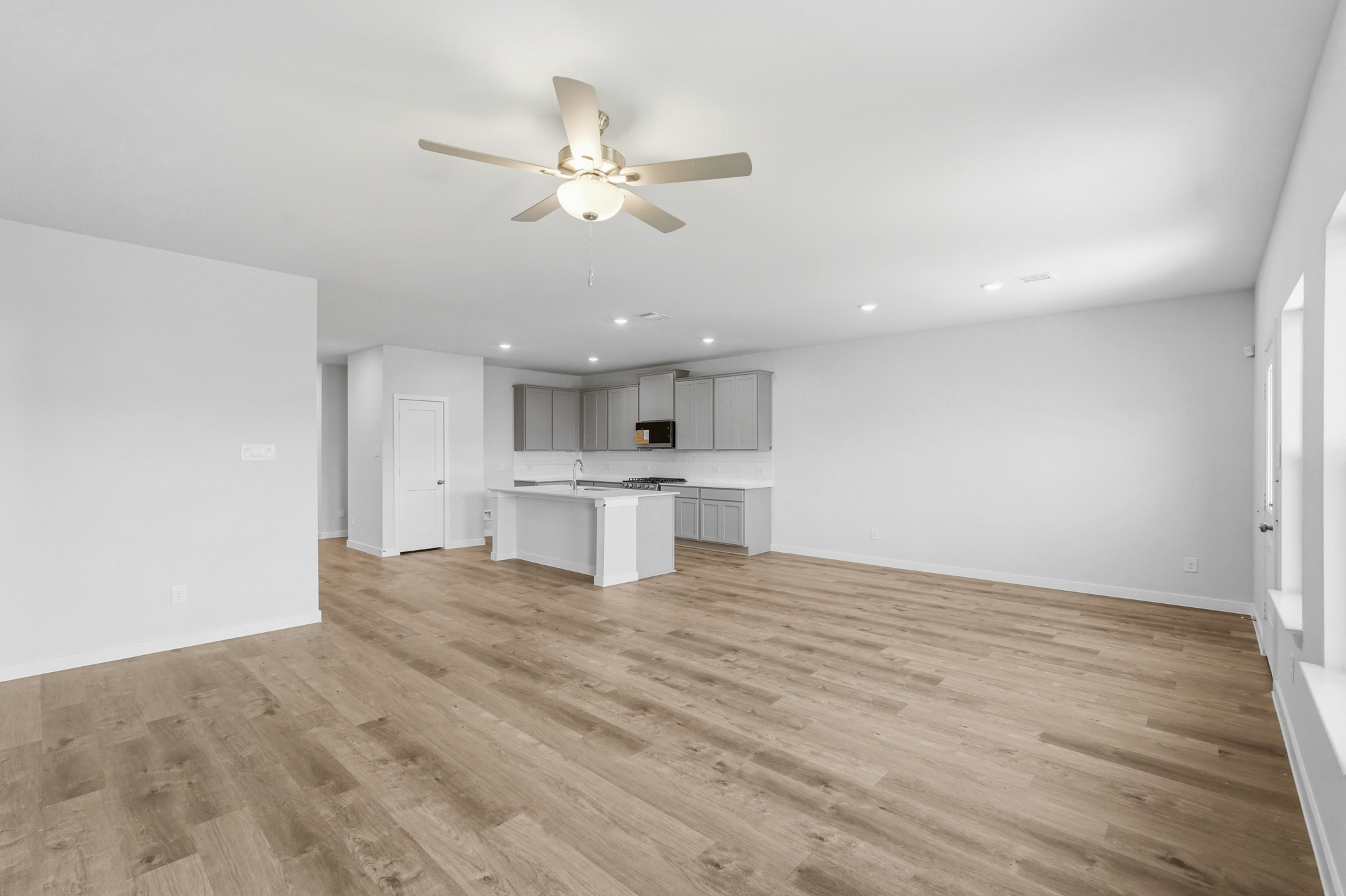A large empty room with a ceiling fan and a wood floor.