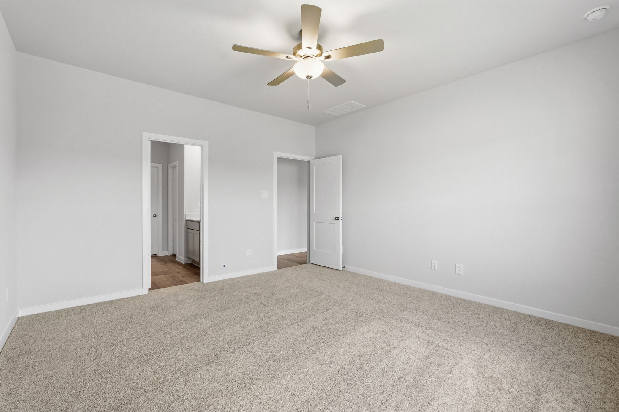 A room with a ceiling fan and a carpet.