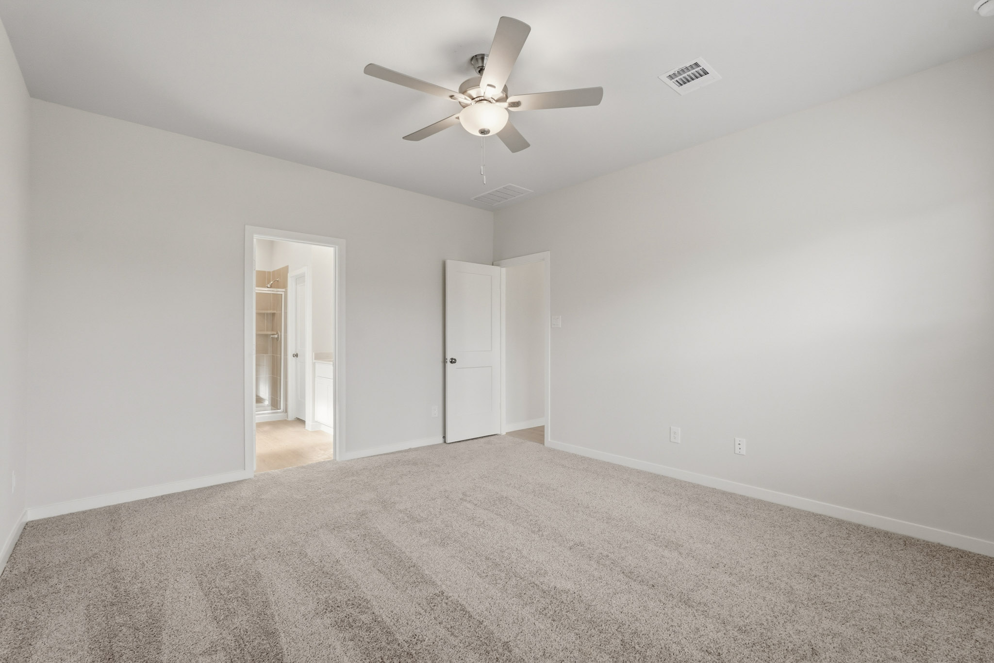 A room with a ceiling fan and a carpet.