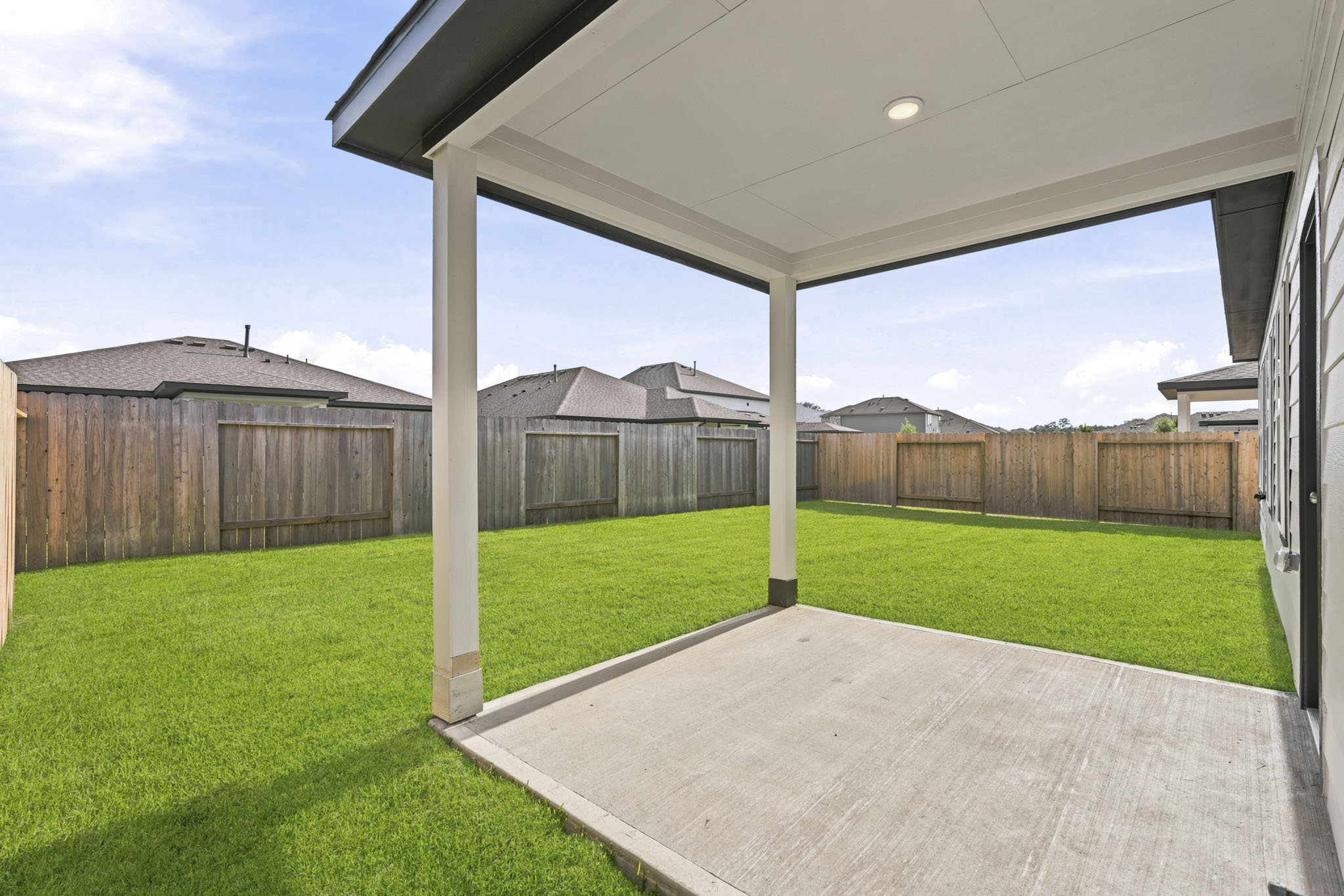 A backyard with a fence and a covered patio.