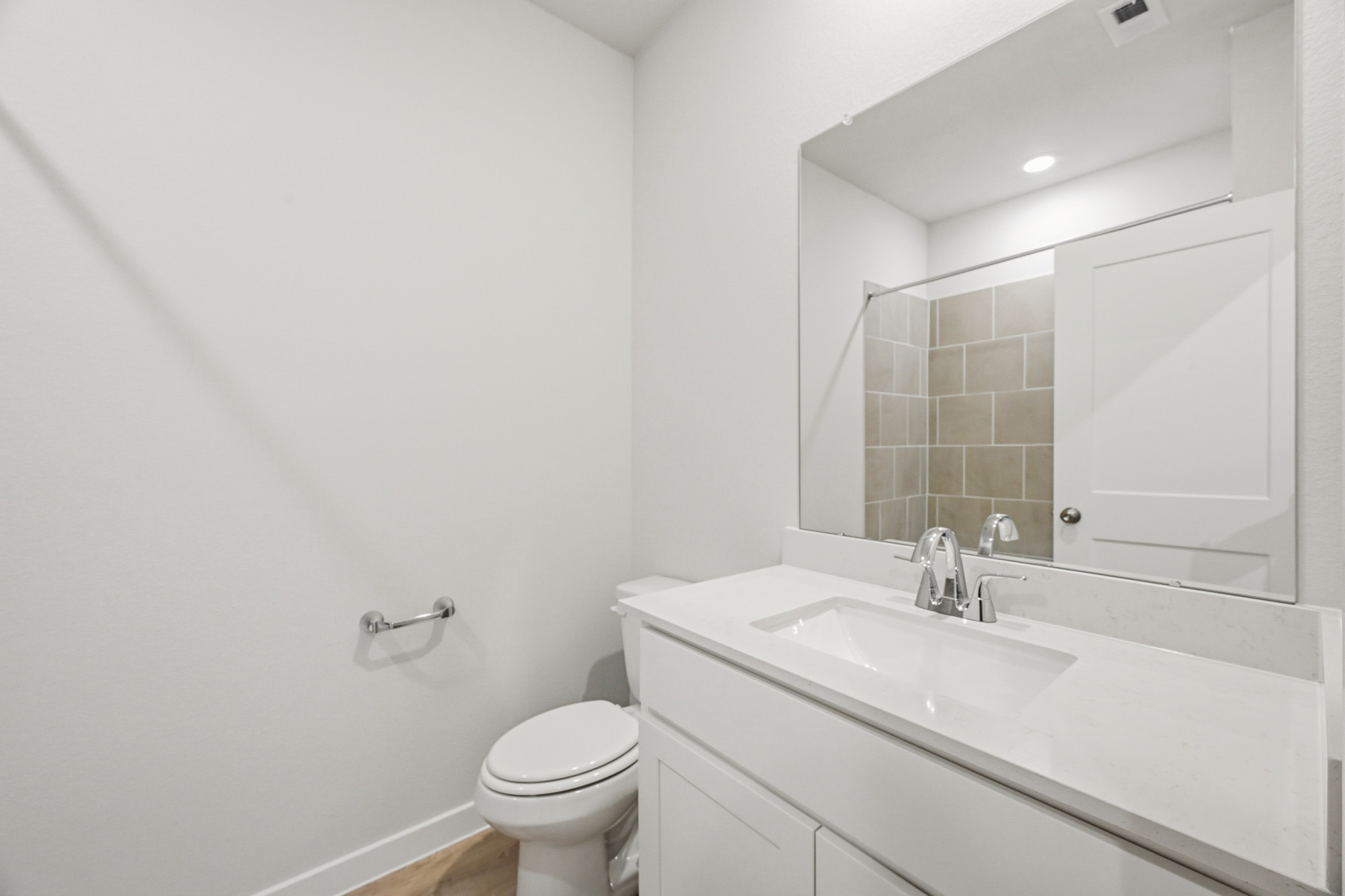 A bathroom with a sink toilet and mirror.
