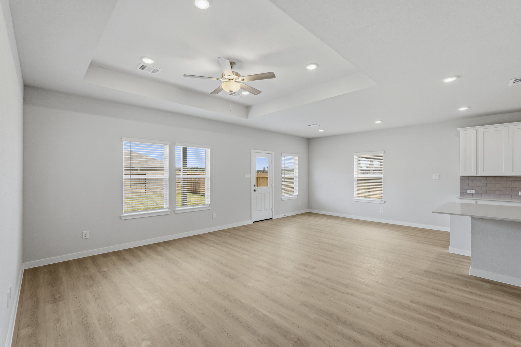 A large empty room with a ceiling fan and a wood floor.