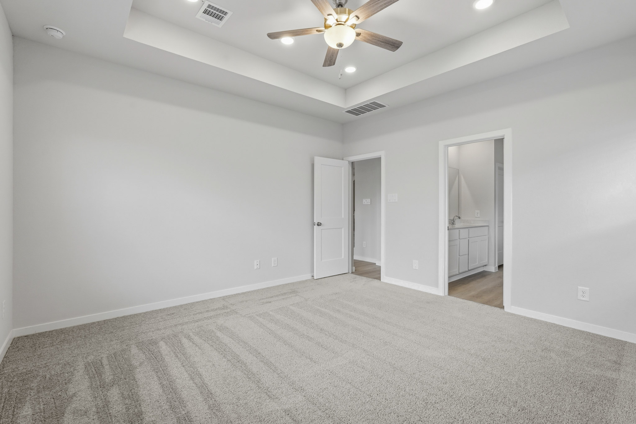 A room with a ceiling fan and a door.