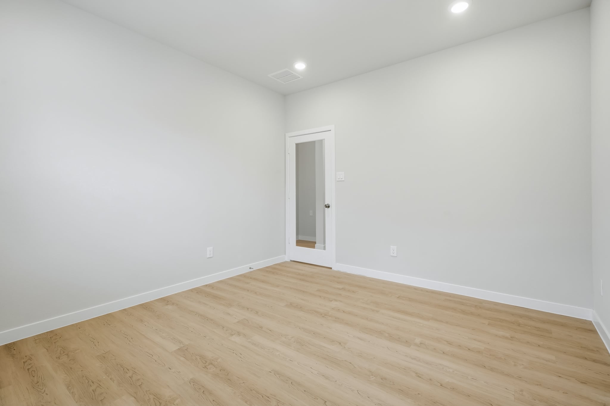 A room with a wood floor and a white door.
