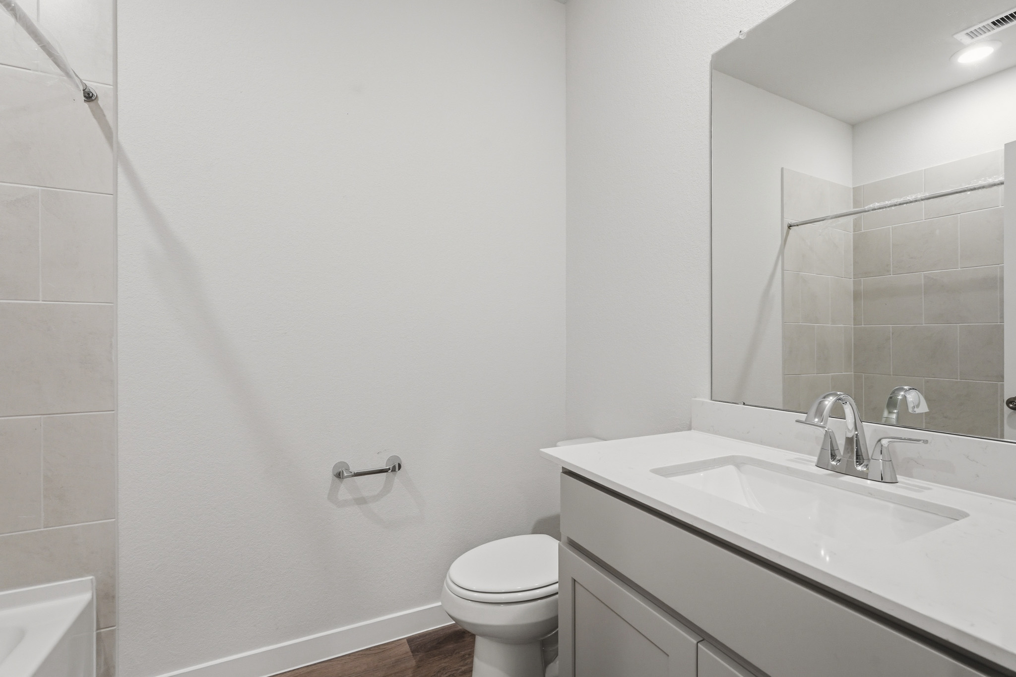 A bathroom with a sink toilet and mirror.
