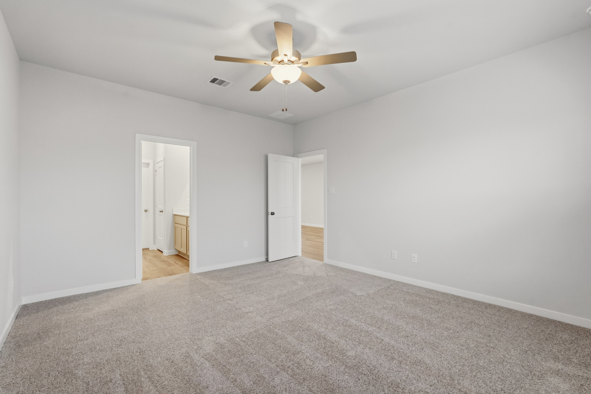 A room with a ceiling fan and carpet.