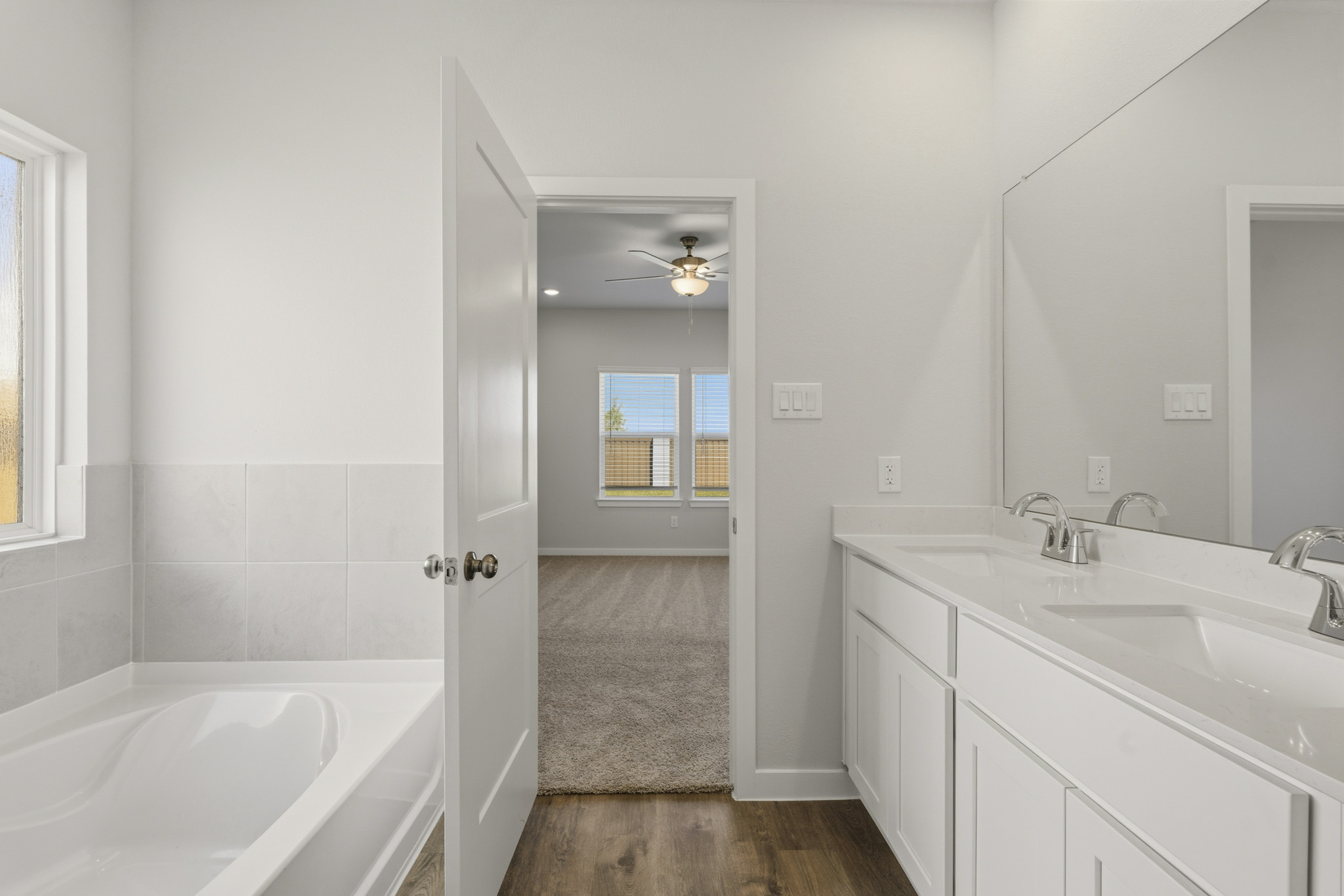 A bathroom with a tub sink and a mirror.
