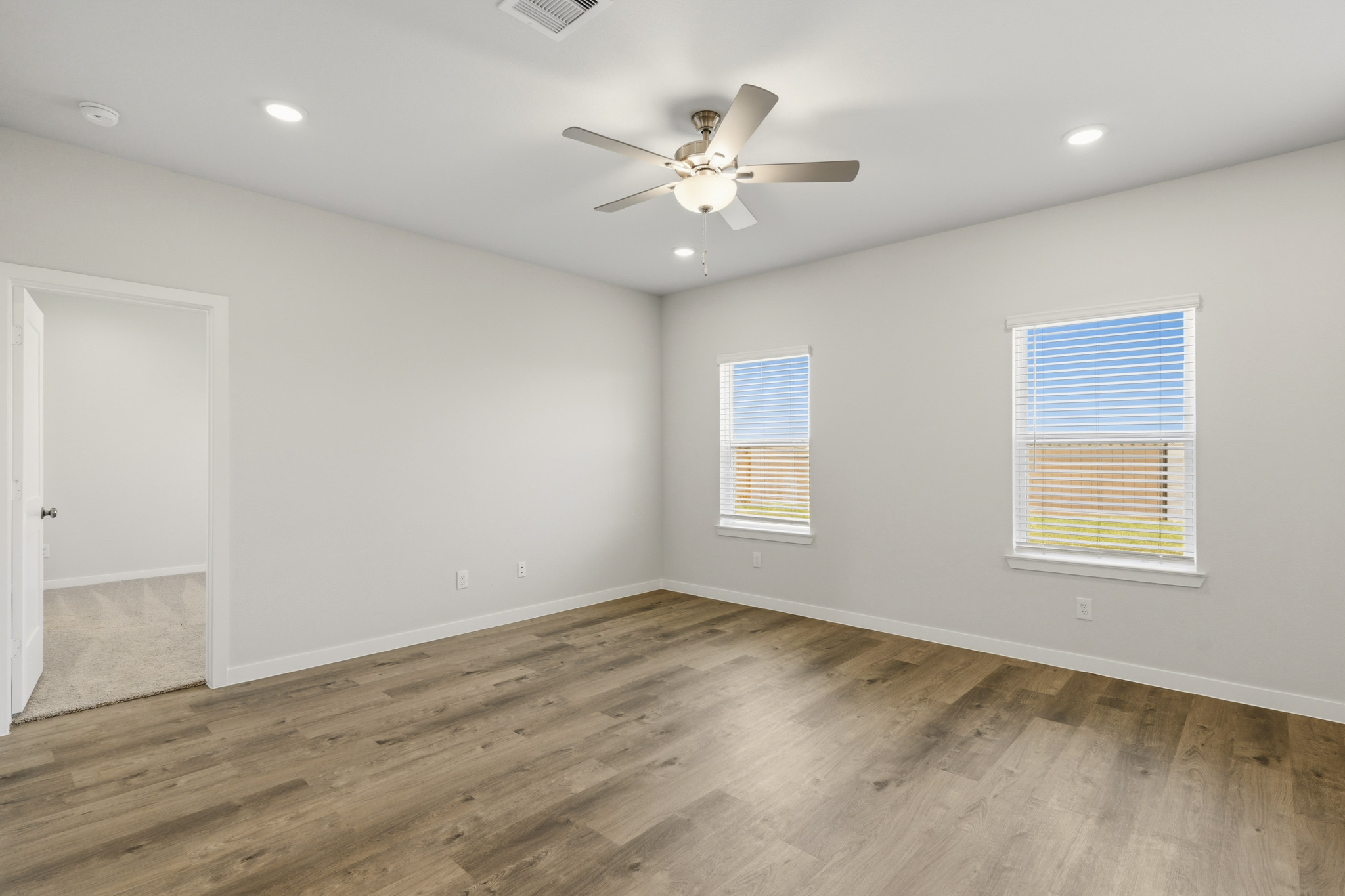 A room with a ceiling fan and wood floor.
