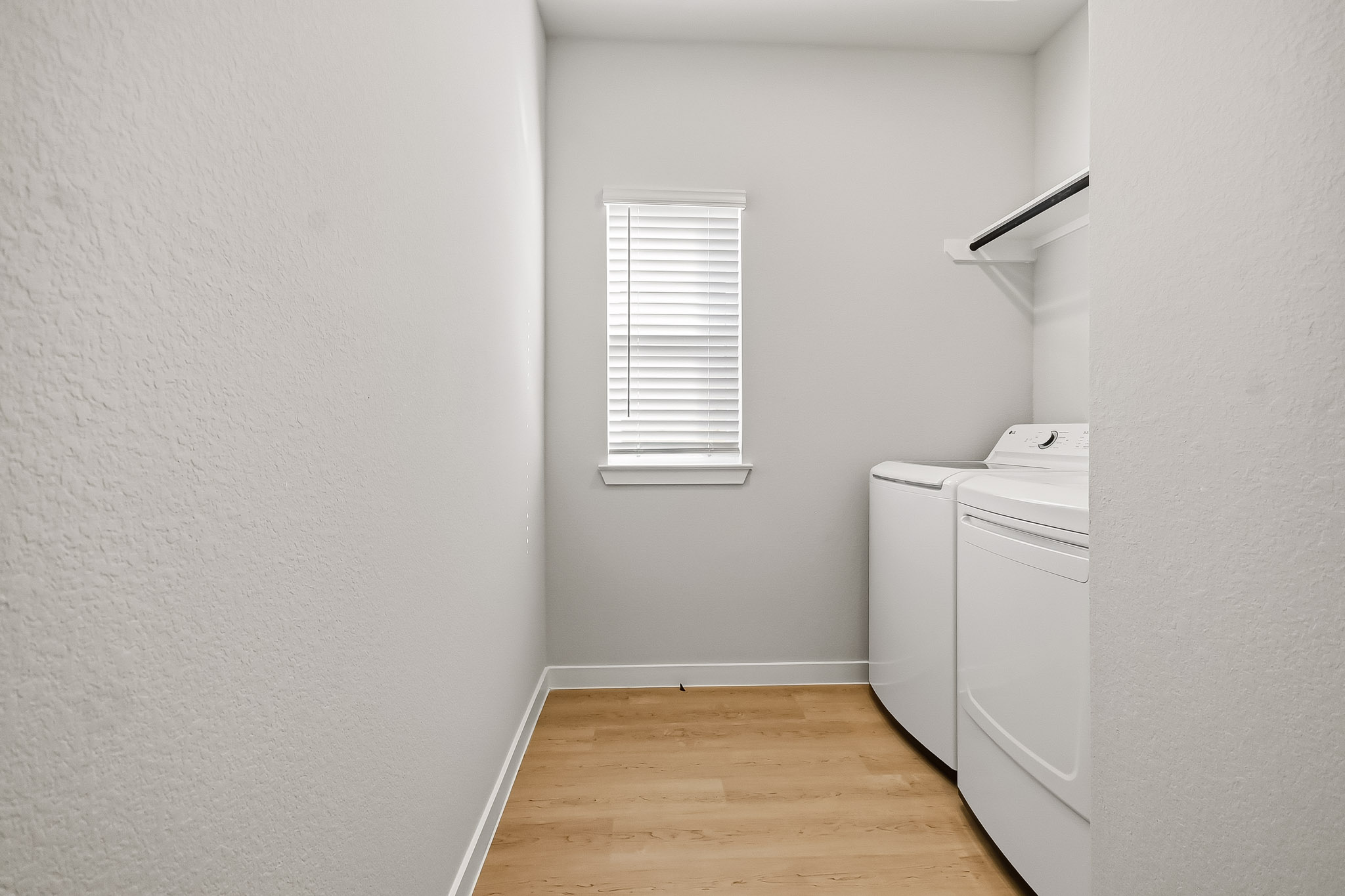 A room with a wood floor and a white wall with a window.