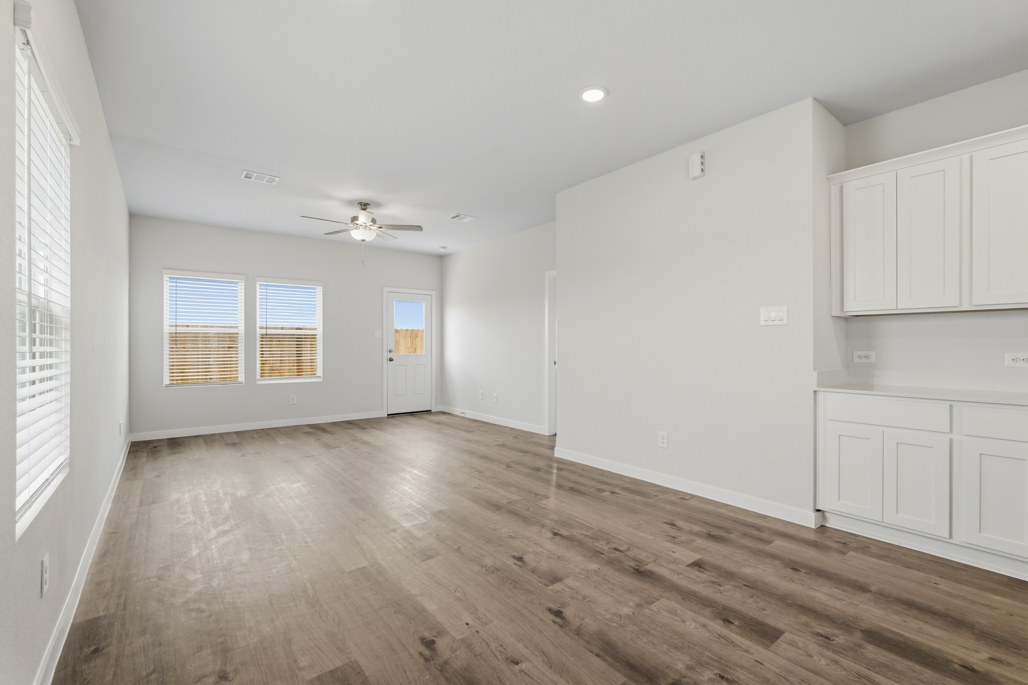 A room with white cabinets and a wood floor.