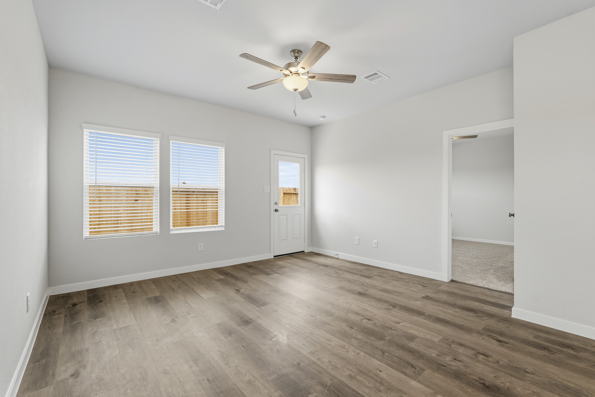 A room with a ceiling fan and a wood floor.