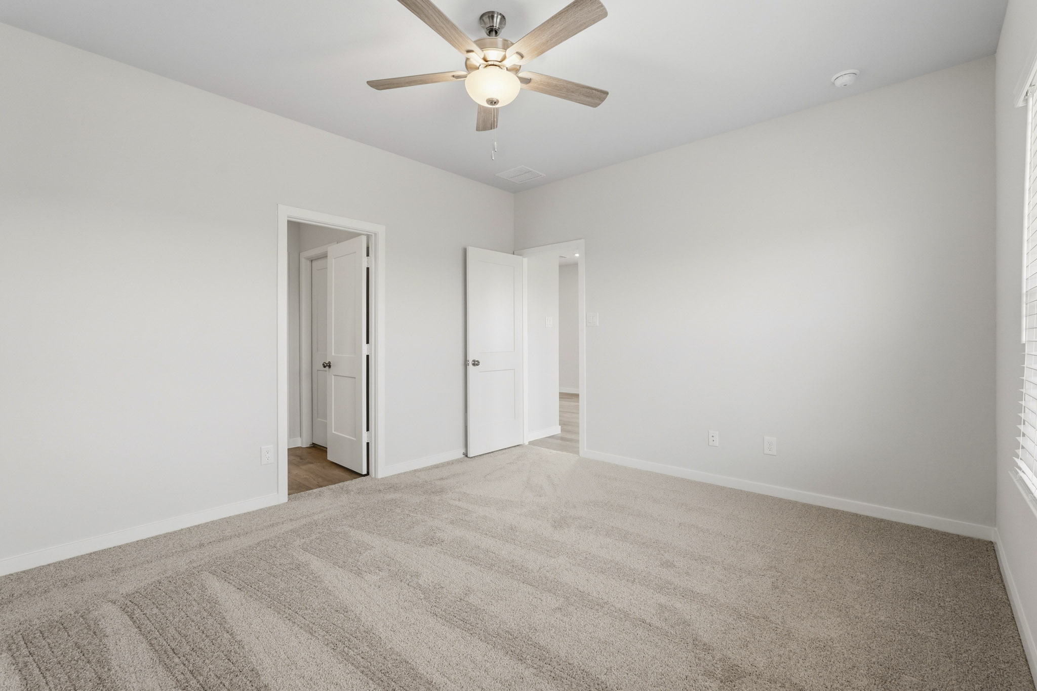 A room with a ceiling fan and a door.
