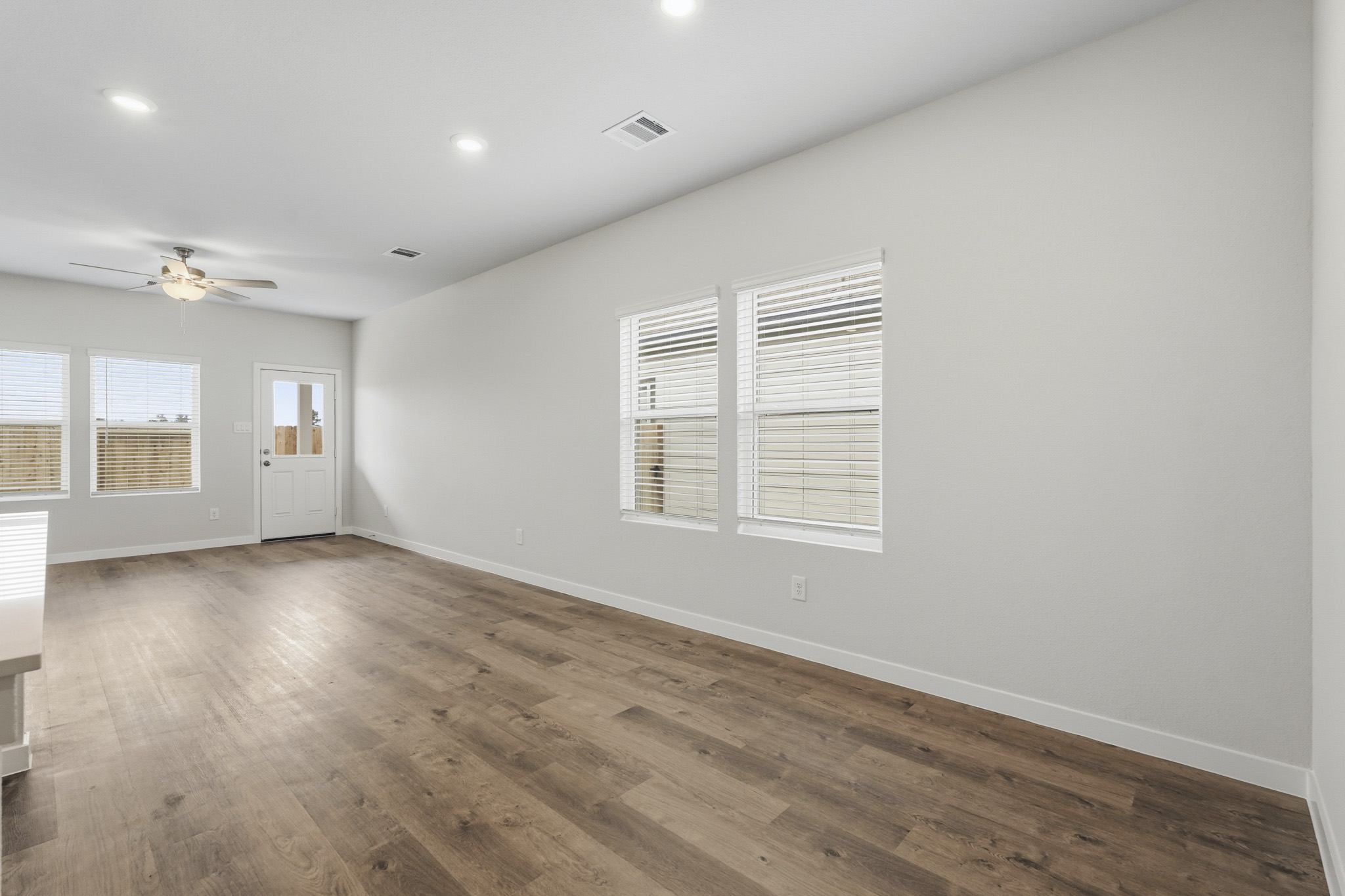 A room with a wood floor and a wood floor with a fan.