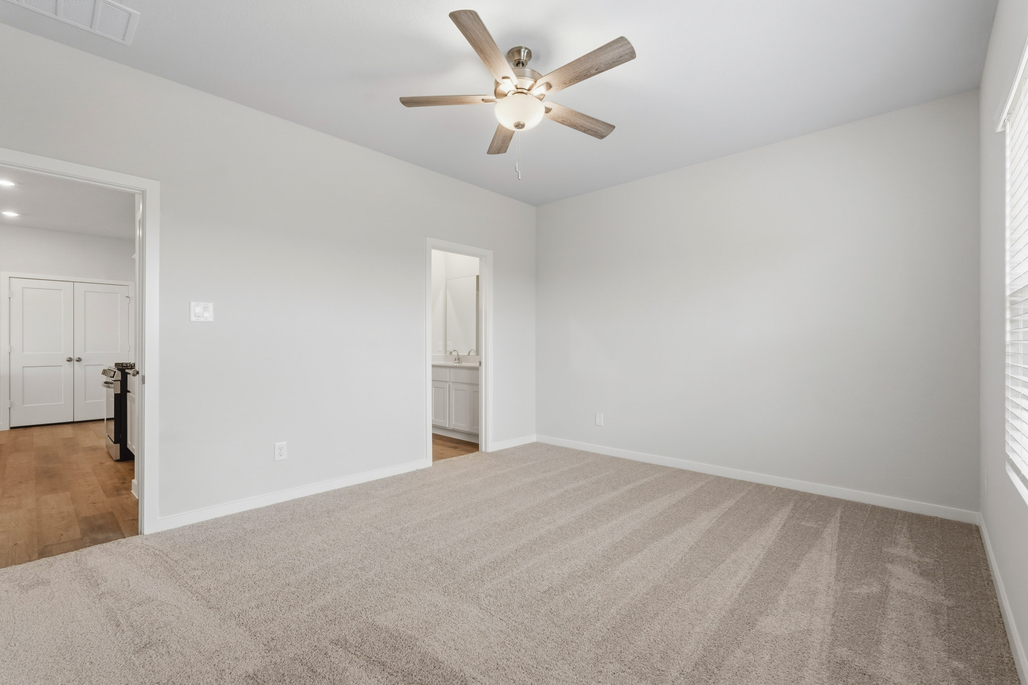 A room with a ceiling fan and a carpet.
