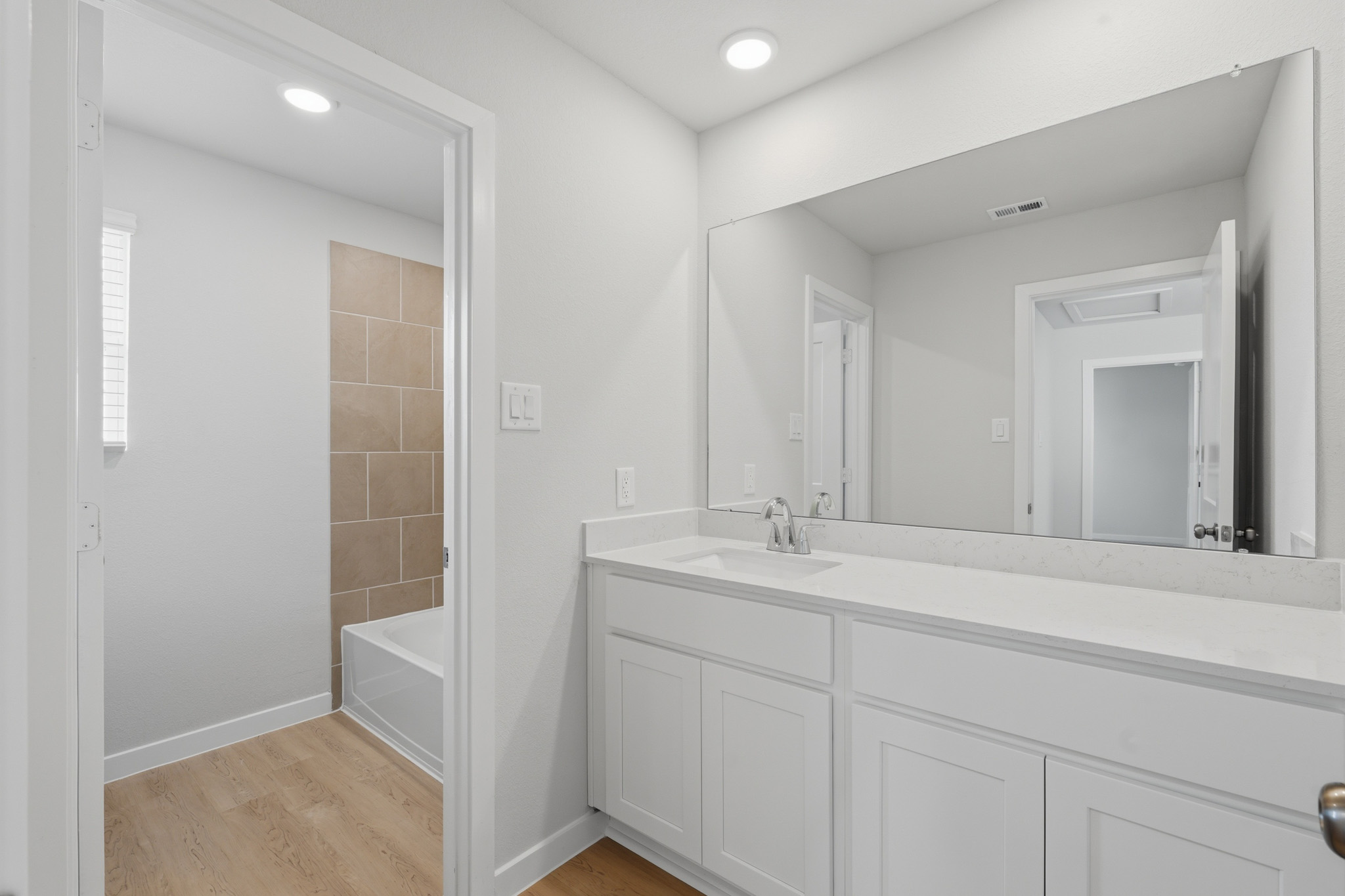 A bathroom with a tub sink and mirror.