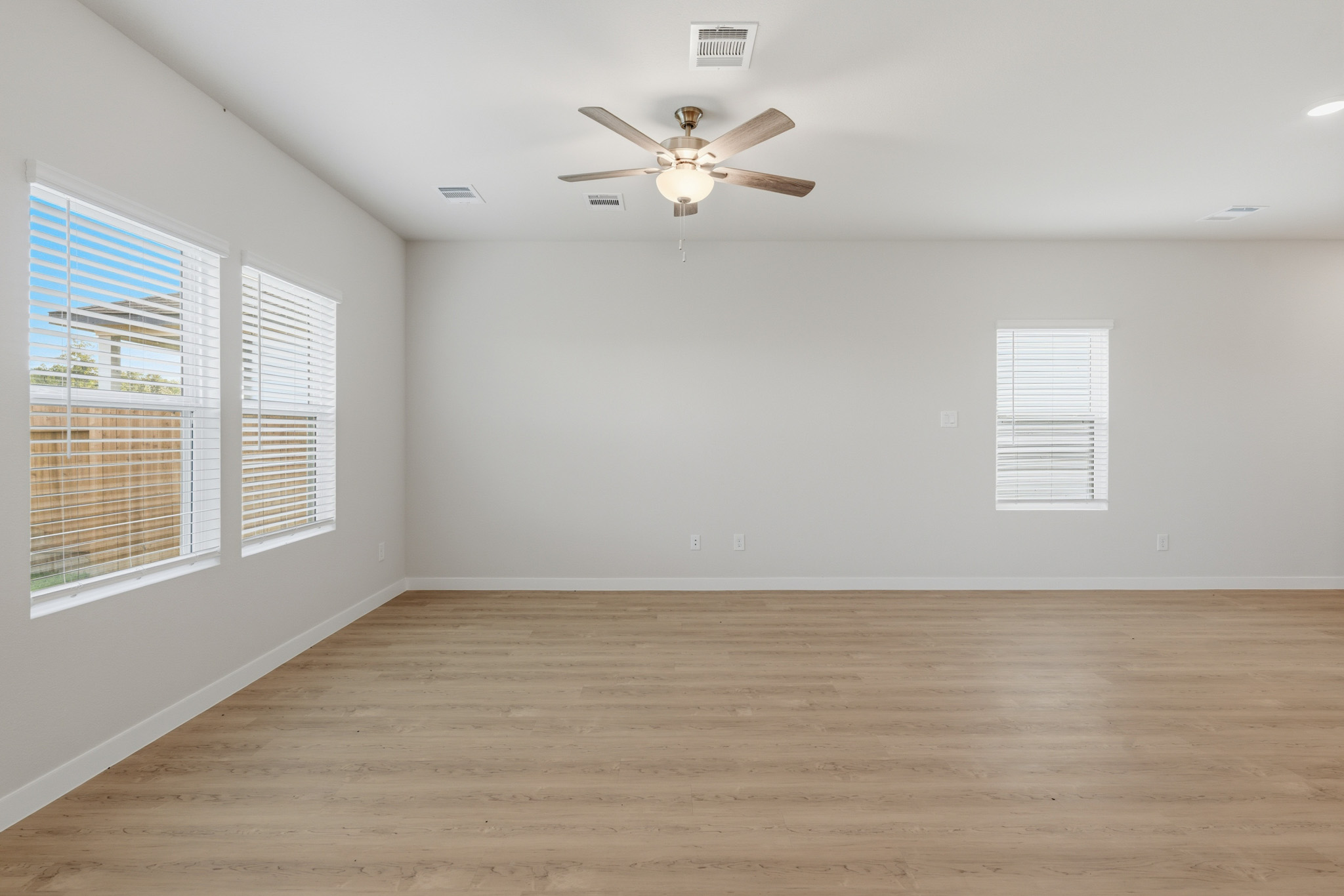 A room with a ceiling fan and a wood floor.