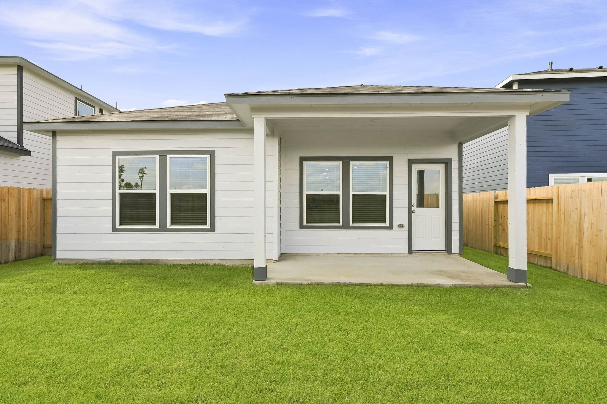 A house with a fence and a lawn in front of it.