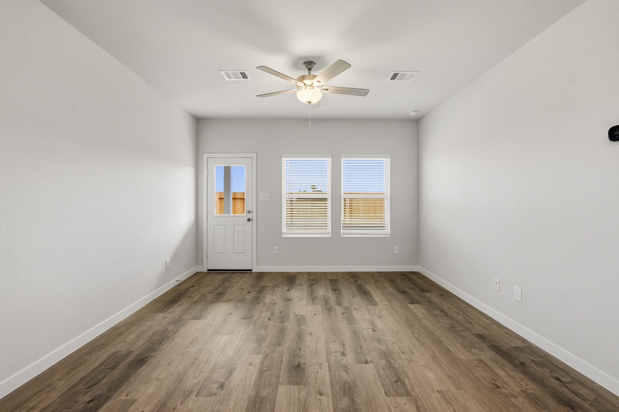 A room with a ceiling fan and a wood floor.