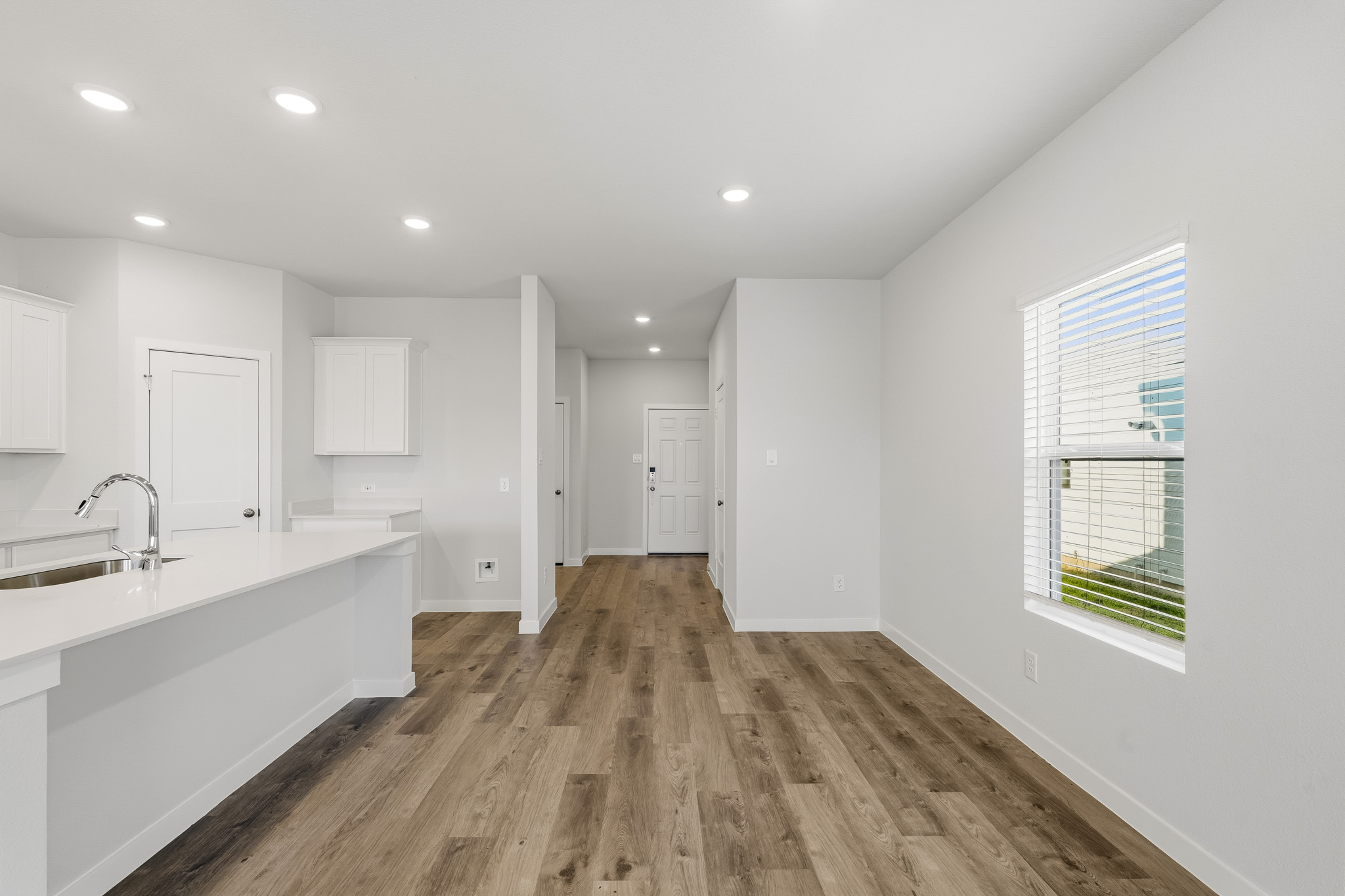 A large white kitchen with a wood floor.