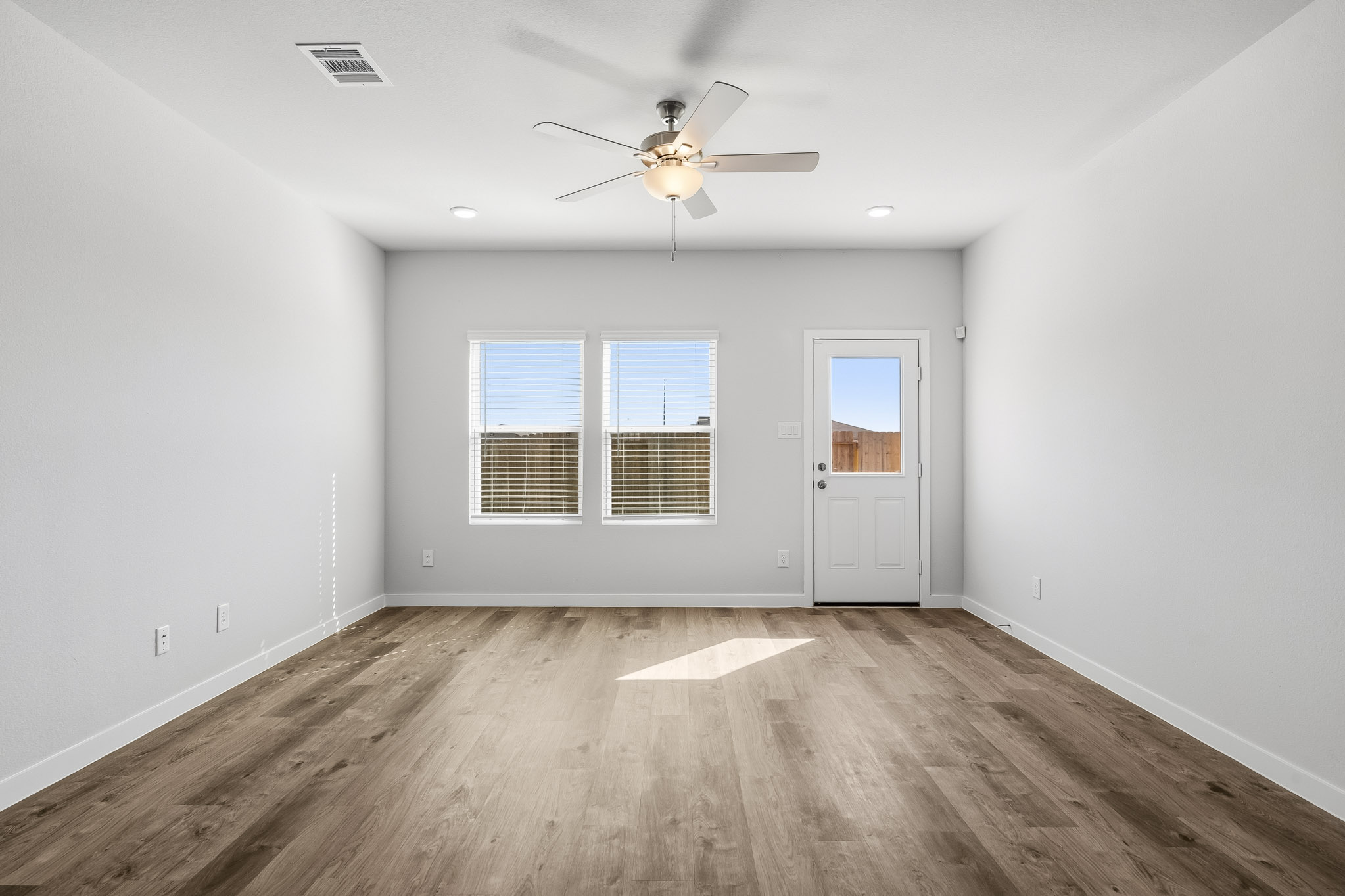 A room with a ceiling fan and a wood floor.
