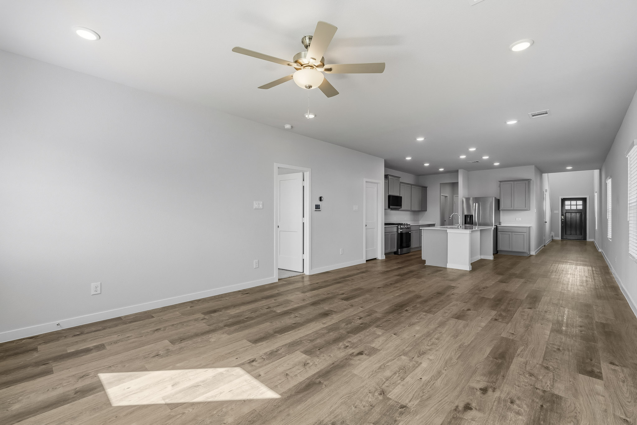 A large empty room with a wood floor and a ceiling fan.