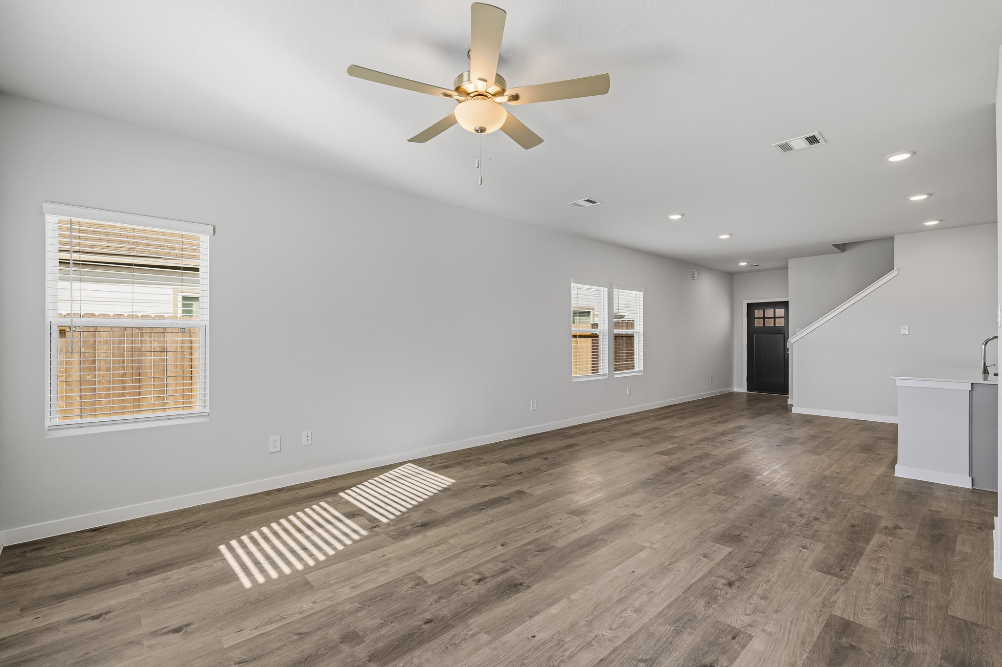 A room with a ceiling fan and wood floor.