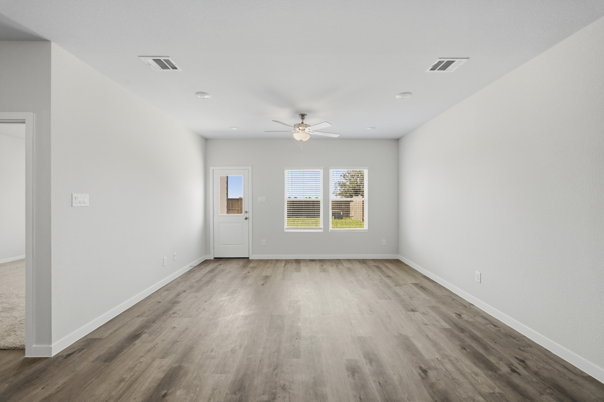 A room with a wood floor and a ceiling fan.