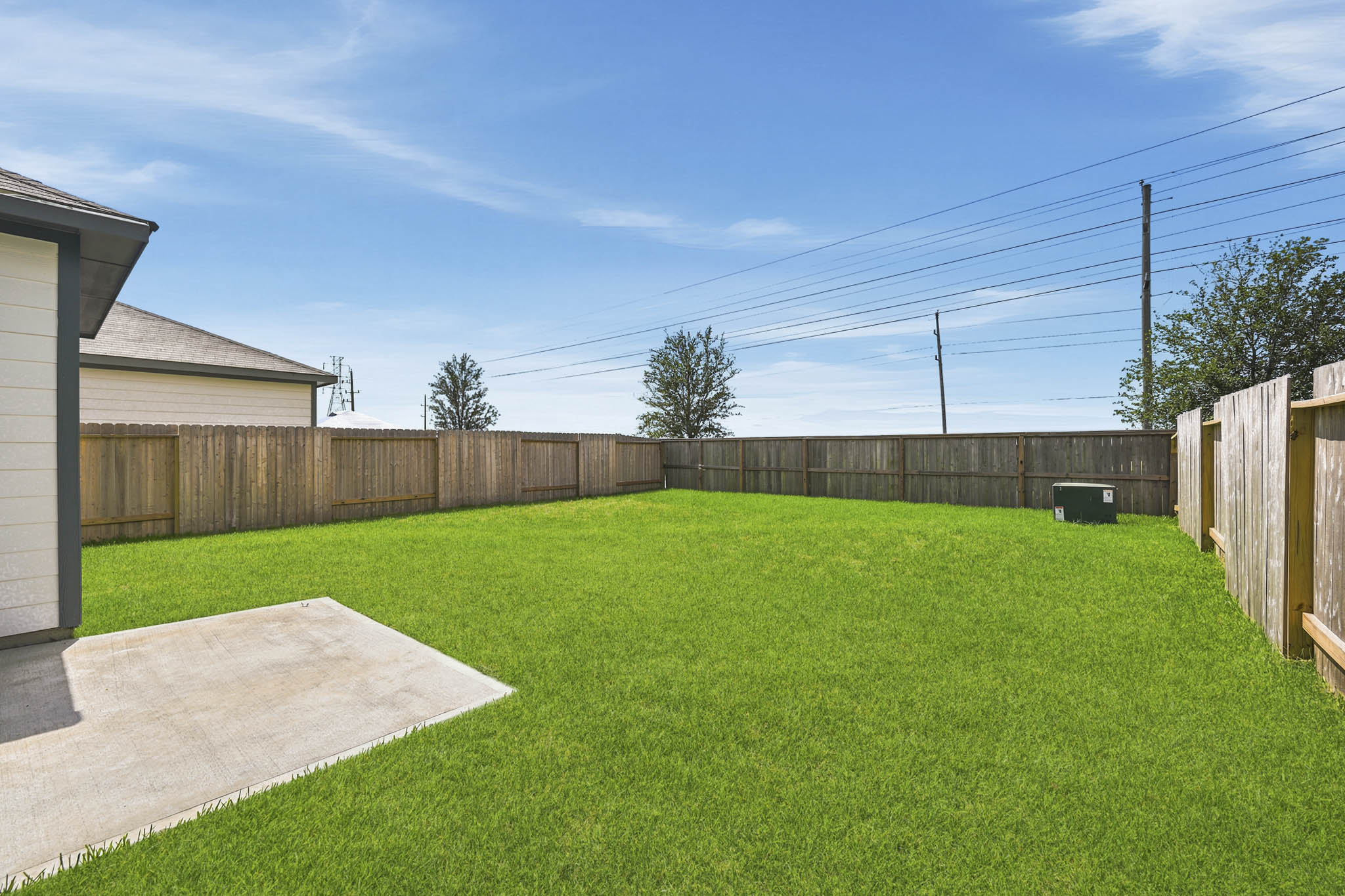 A backyard with a fence and a lawn.