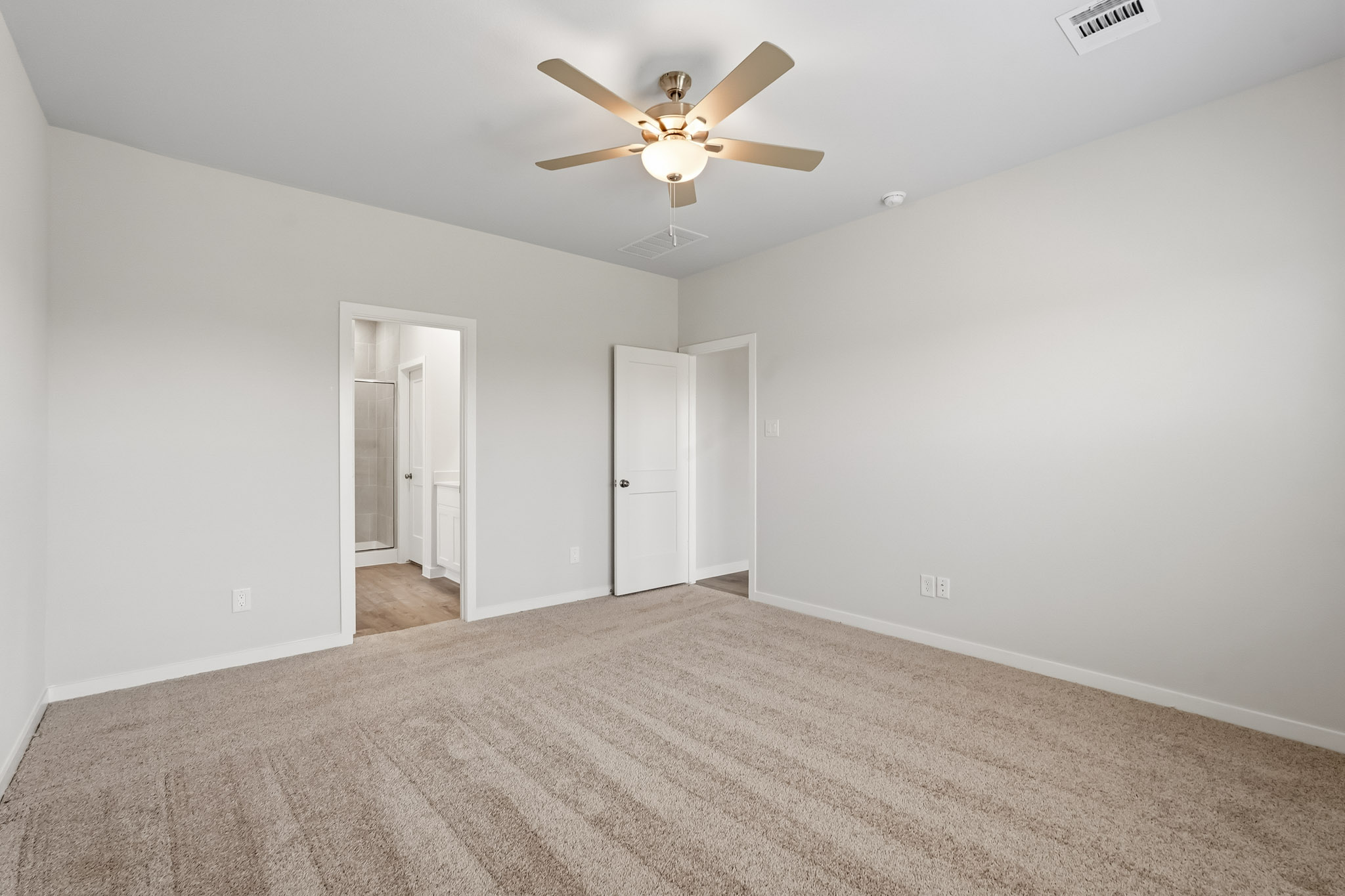 A room with a ceiling fan and a carpet.
