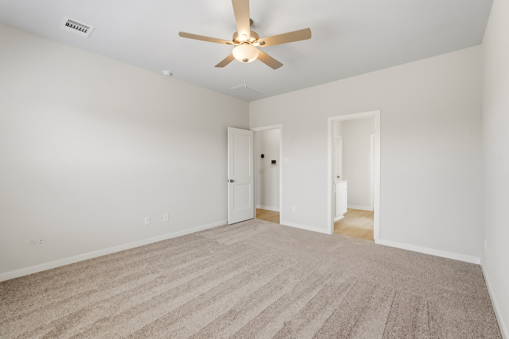 A room with a ceiling fan and a carpet.