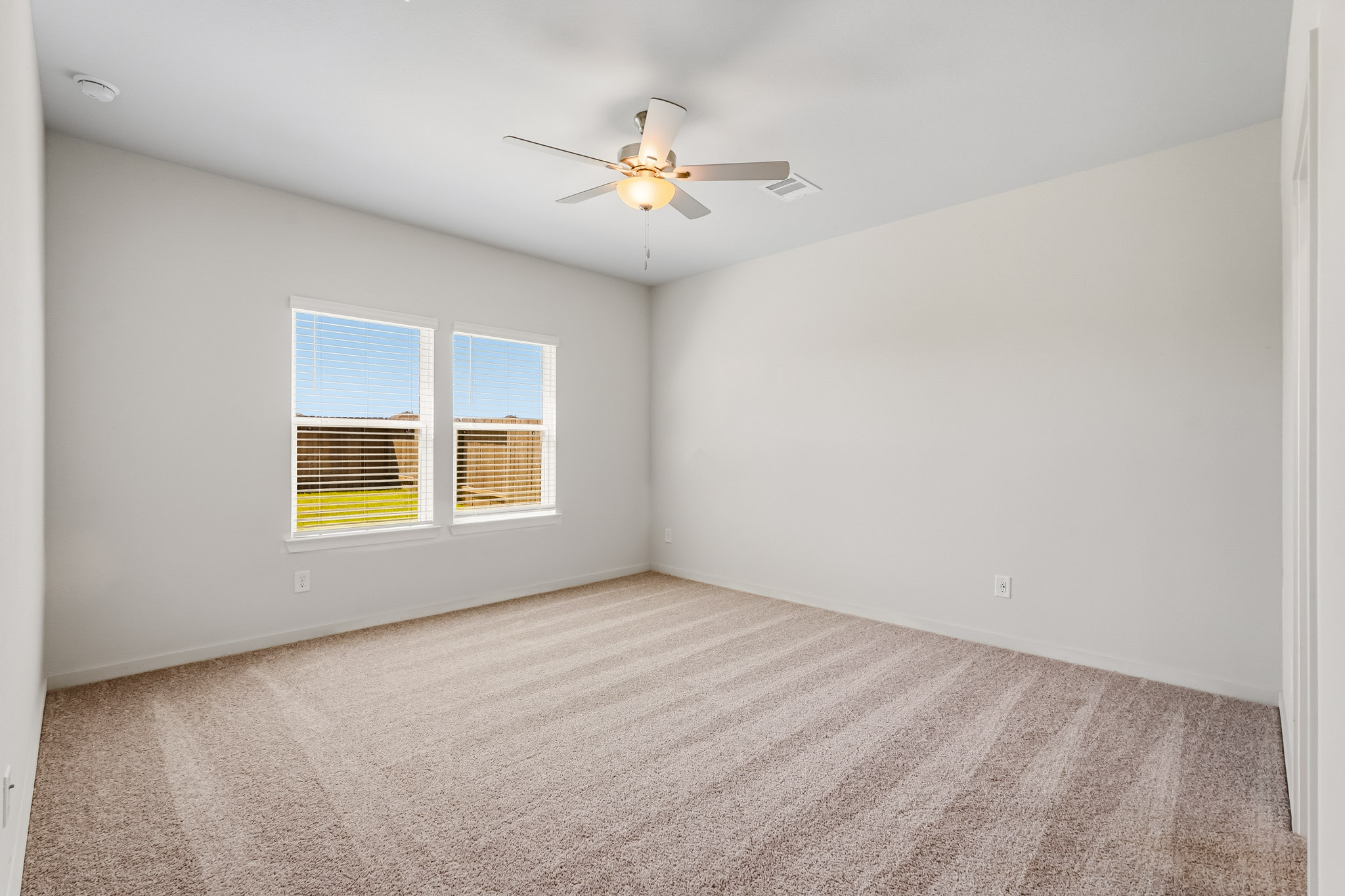 A room with a ceiling fan and a carpet.