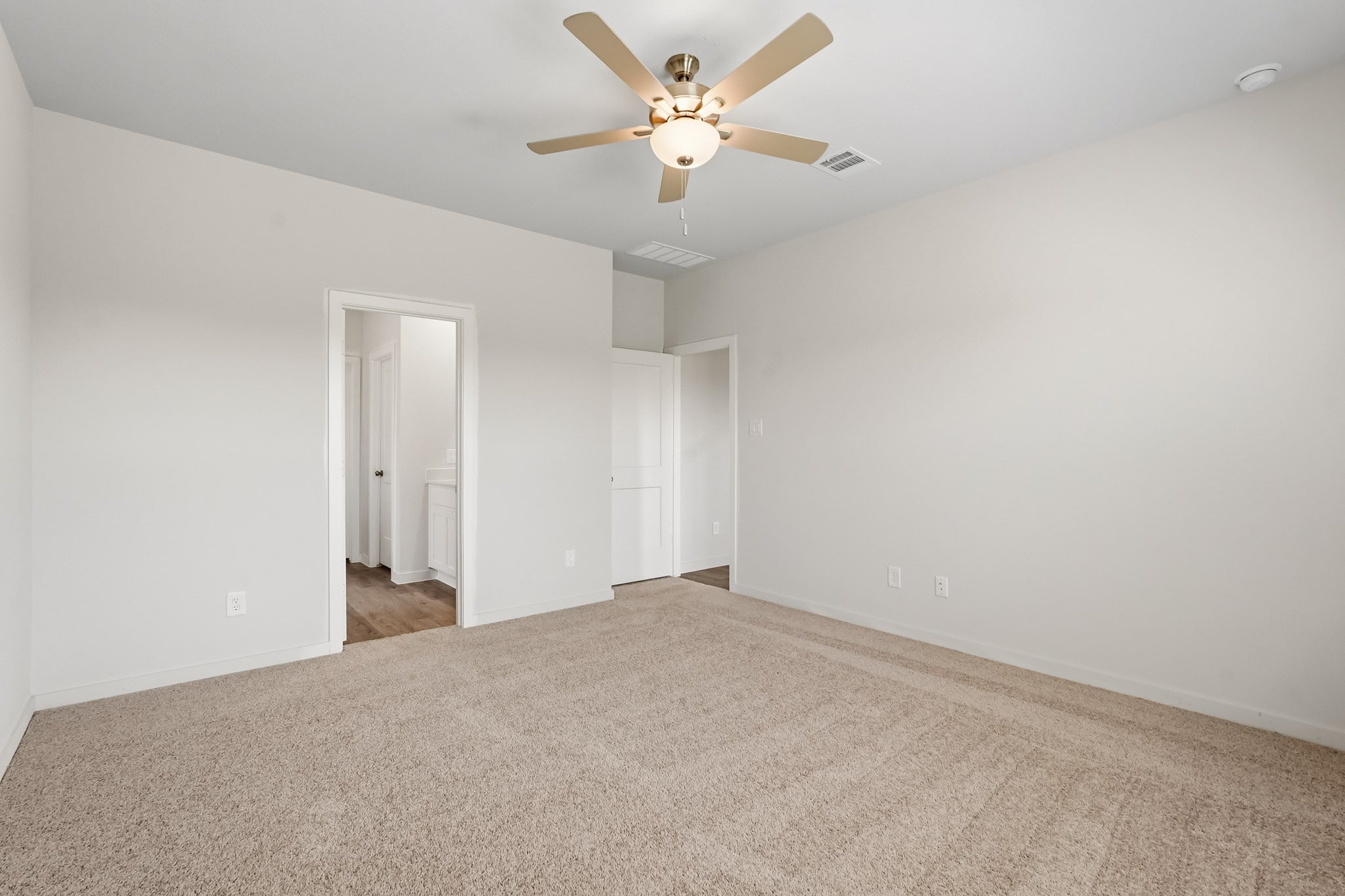 A room with a ceiling fan and carpet.