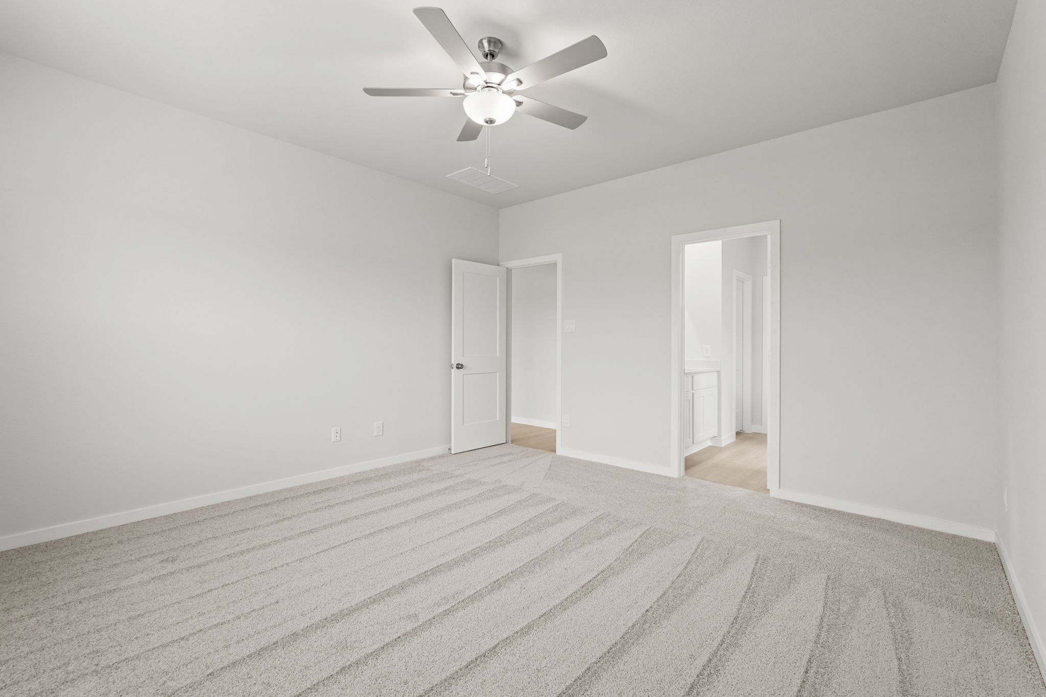 A room with a ceiling fan and a carpet.
