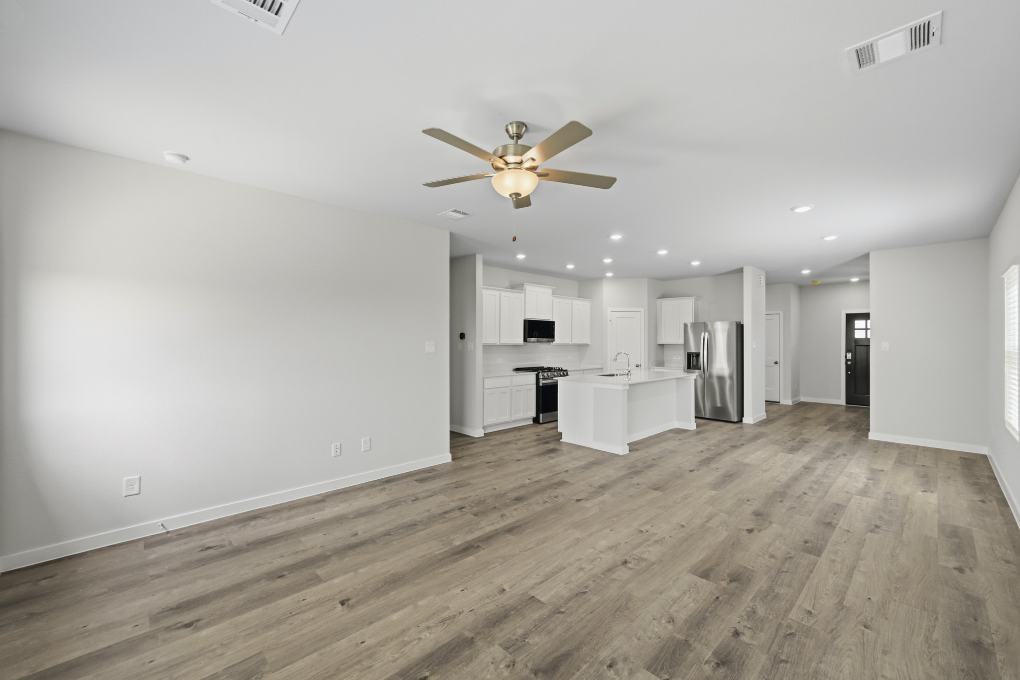 A large empty room with a wood floor and a ceiling fan.