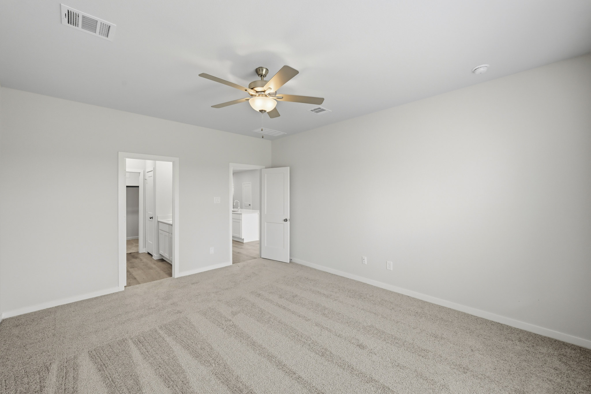 A room with a ceiling fan and a carpet.