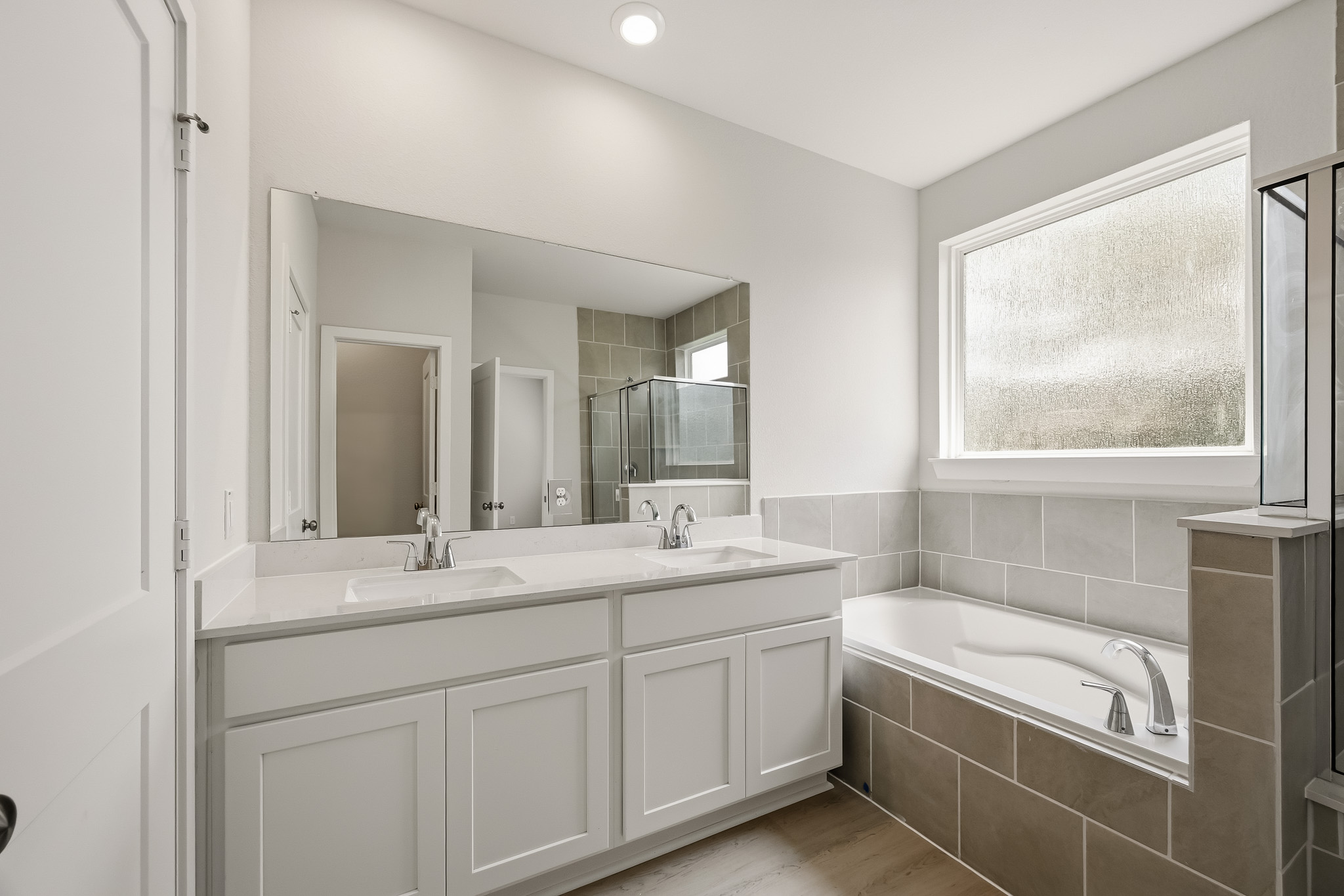 A bathroom with a tub sink and mirror.