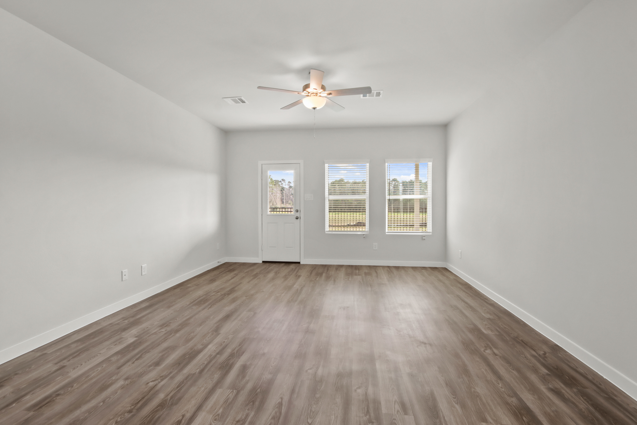 A room with a ceiling fan and a wood floor.