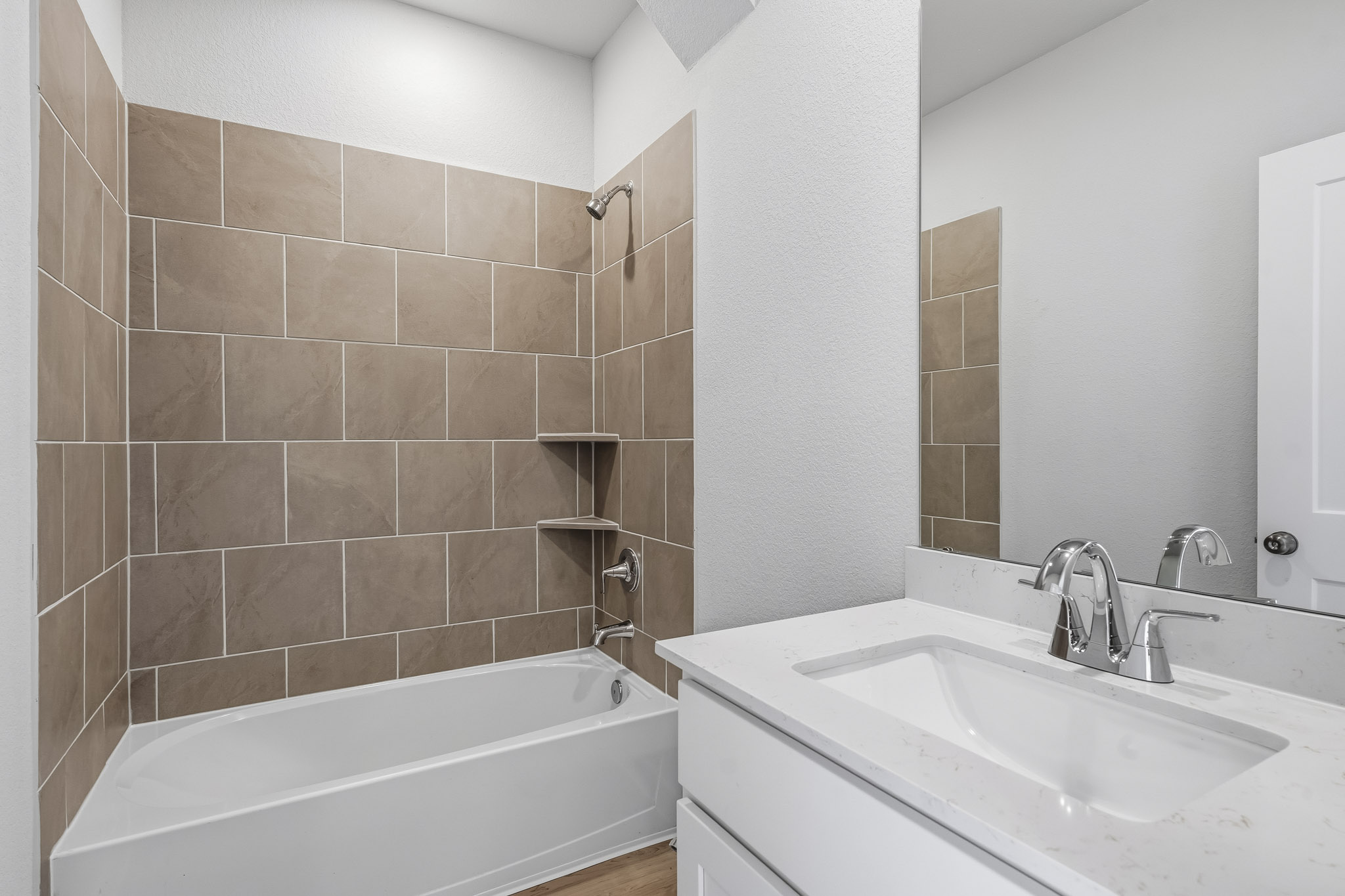A bathroom with a tub sink and a mirror.