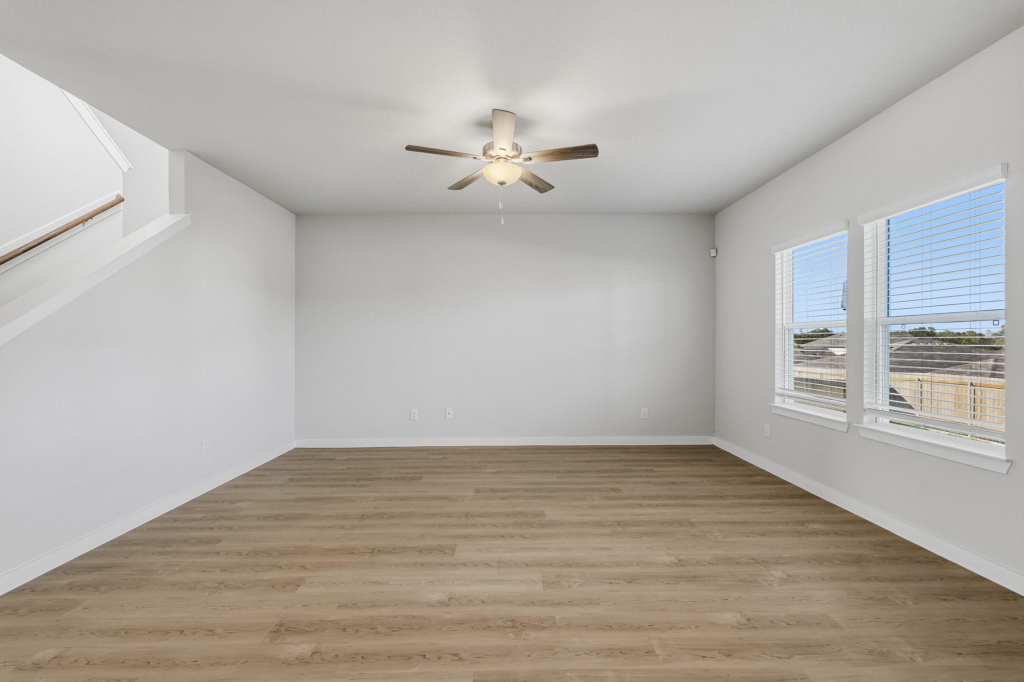 A room with a ceiling fan and a wood floor.
