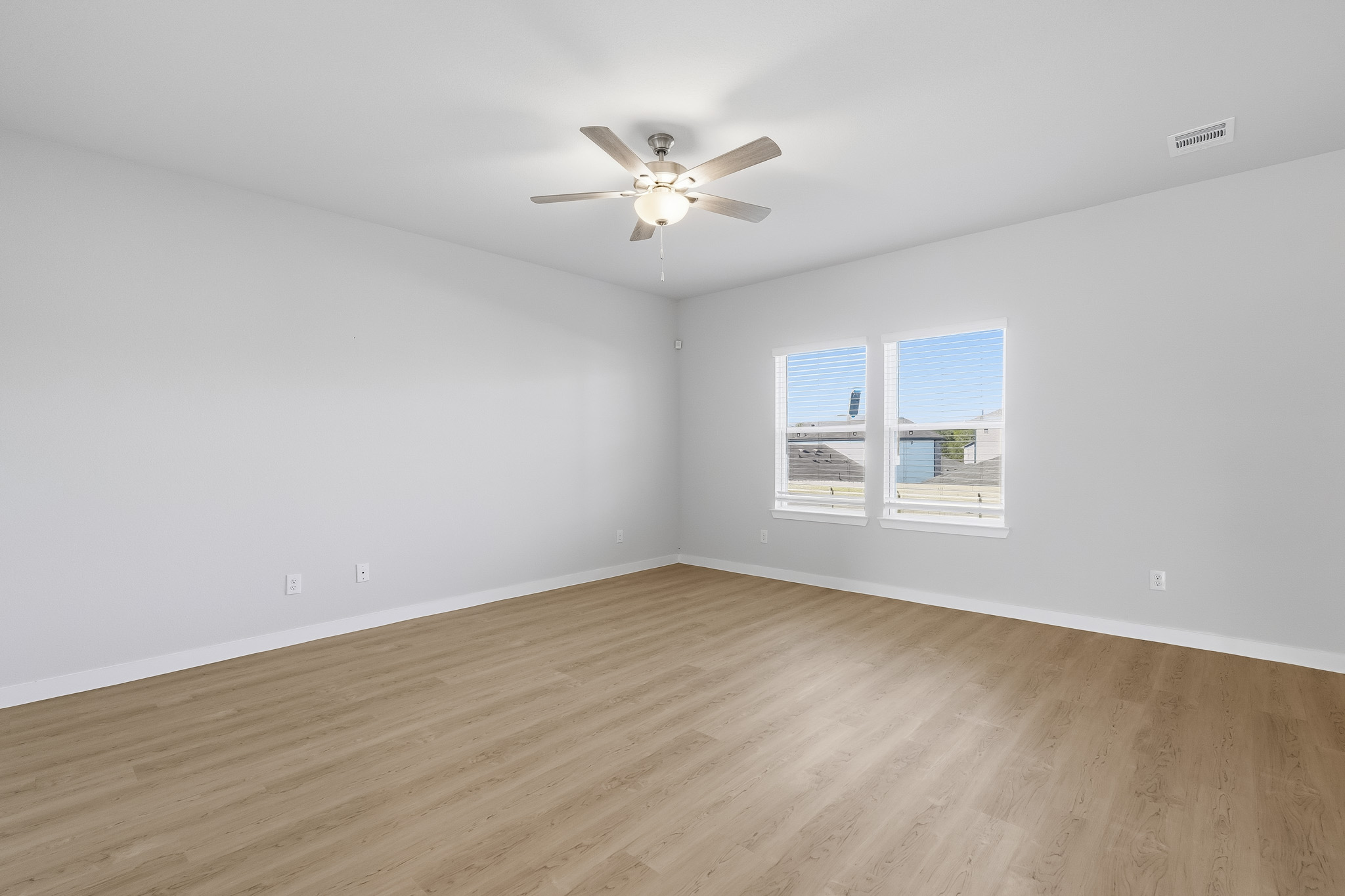 A room with a ceiling fan and a wood floor.
