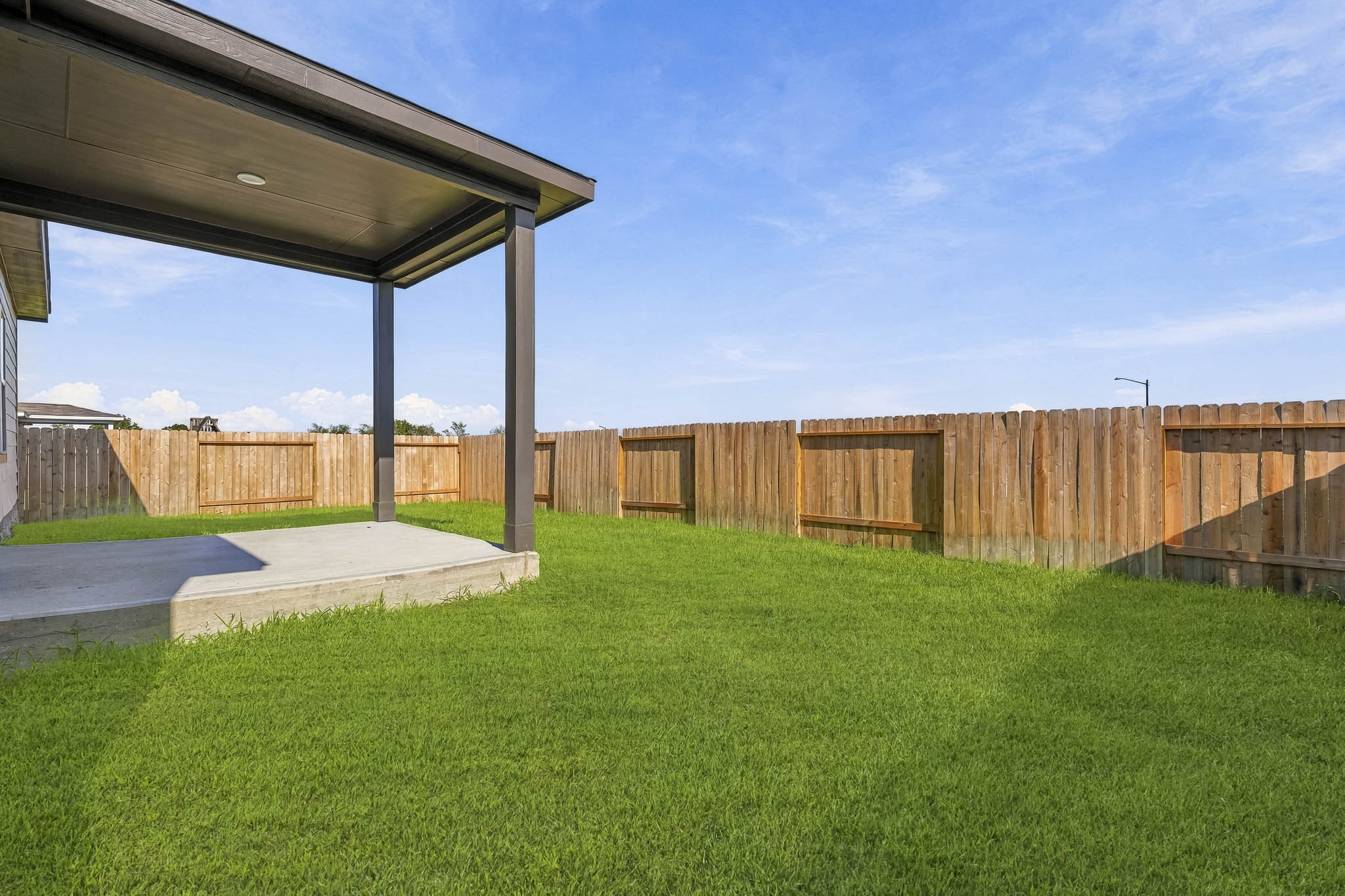 A fenced in yard with a covered patio and a covered patio.