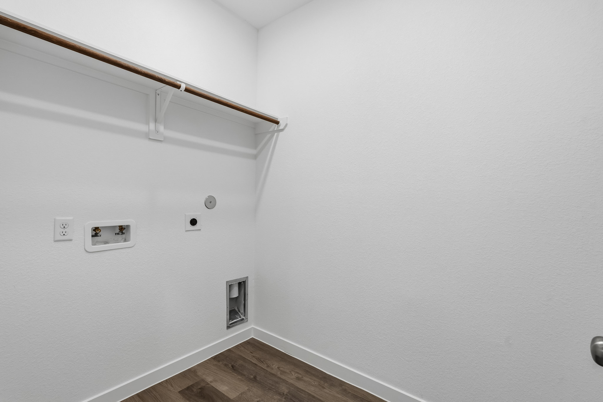 A white wall with a wood floor.