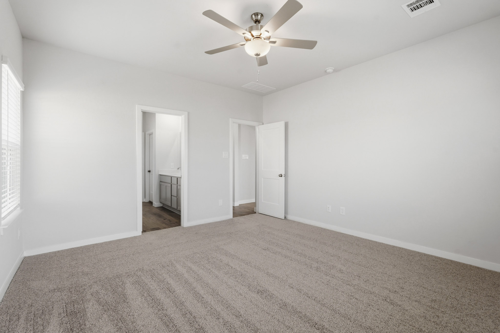 A room with a ceiling fan and a carpet.