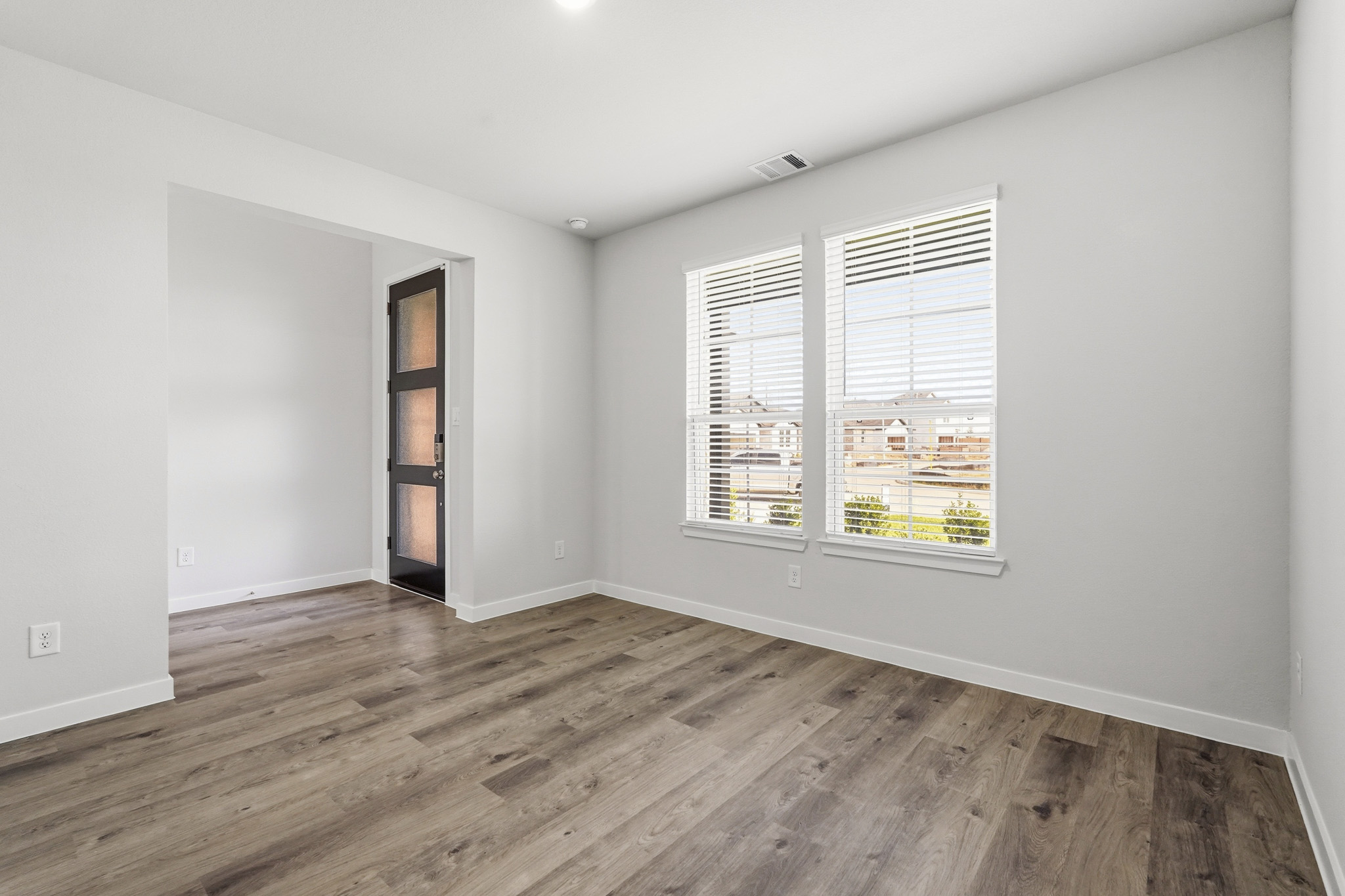 A room with a wood floor and a window with blinds.