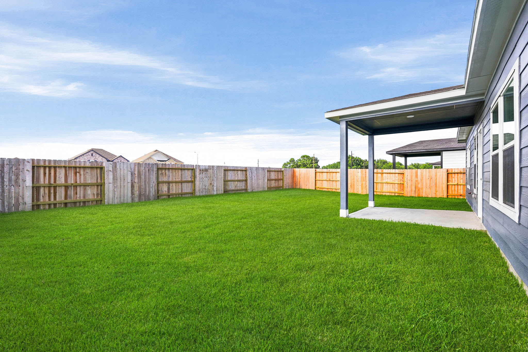 A fenced in yard with a house and a building in the background.