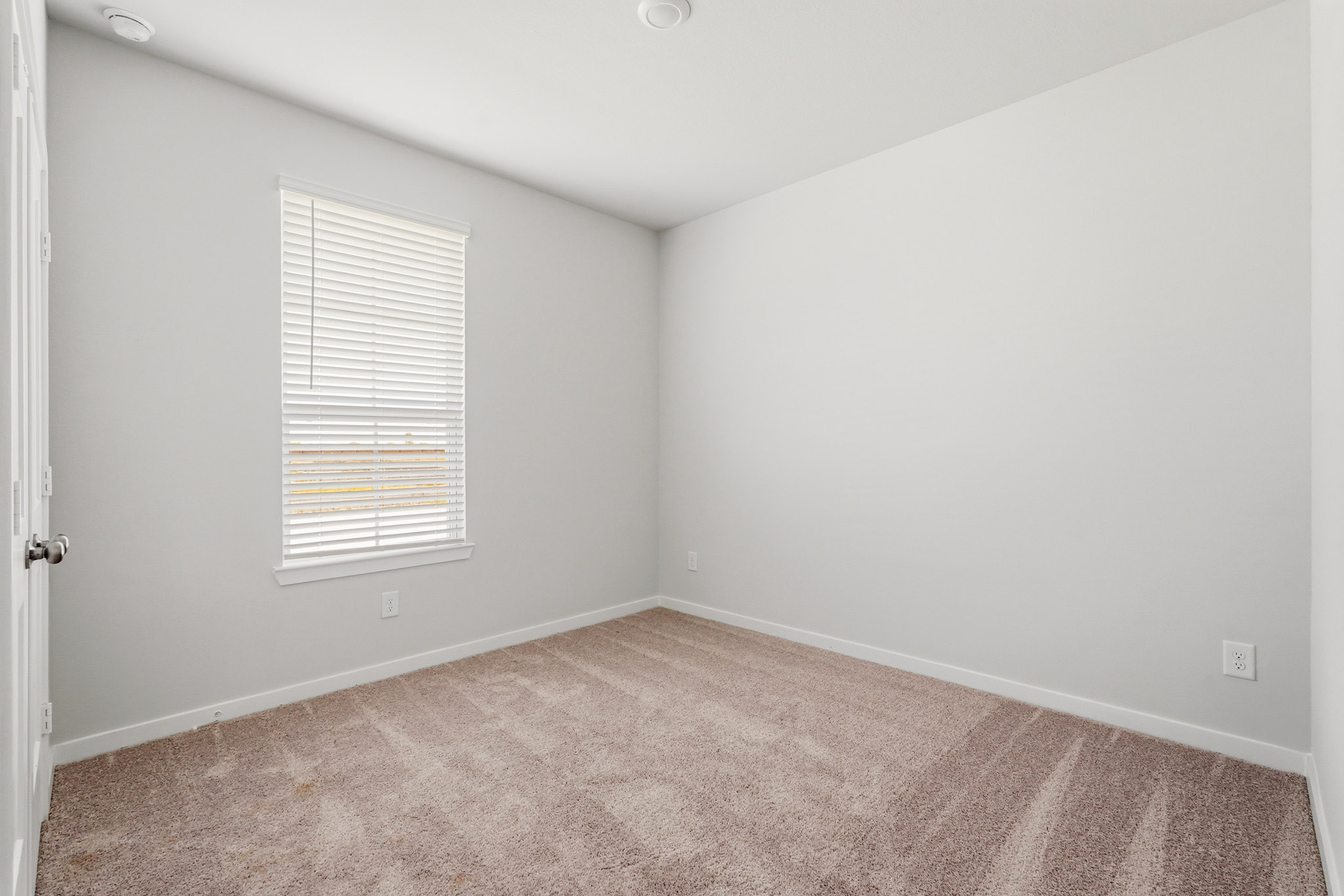 A room with a carpet and a window.