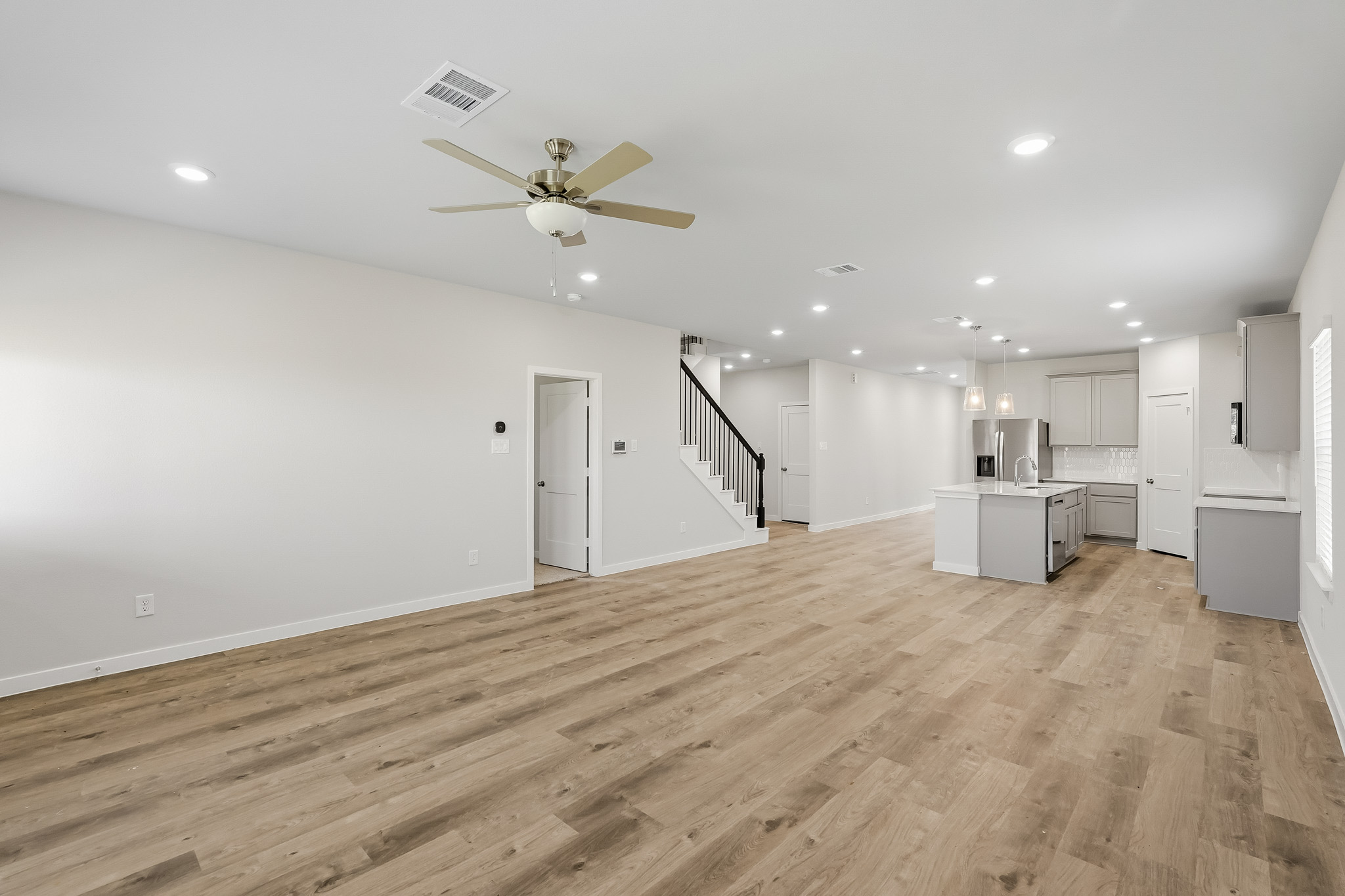 A large empty room with a wood floor and a ceiling fan.