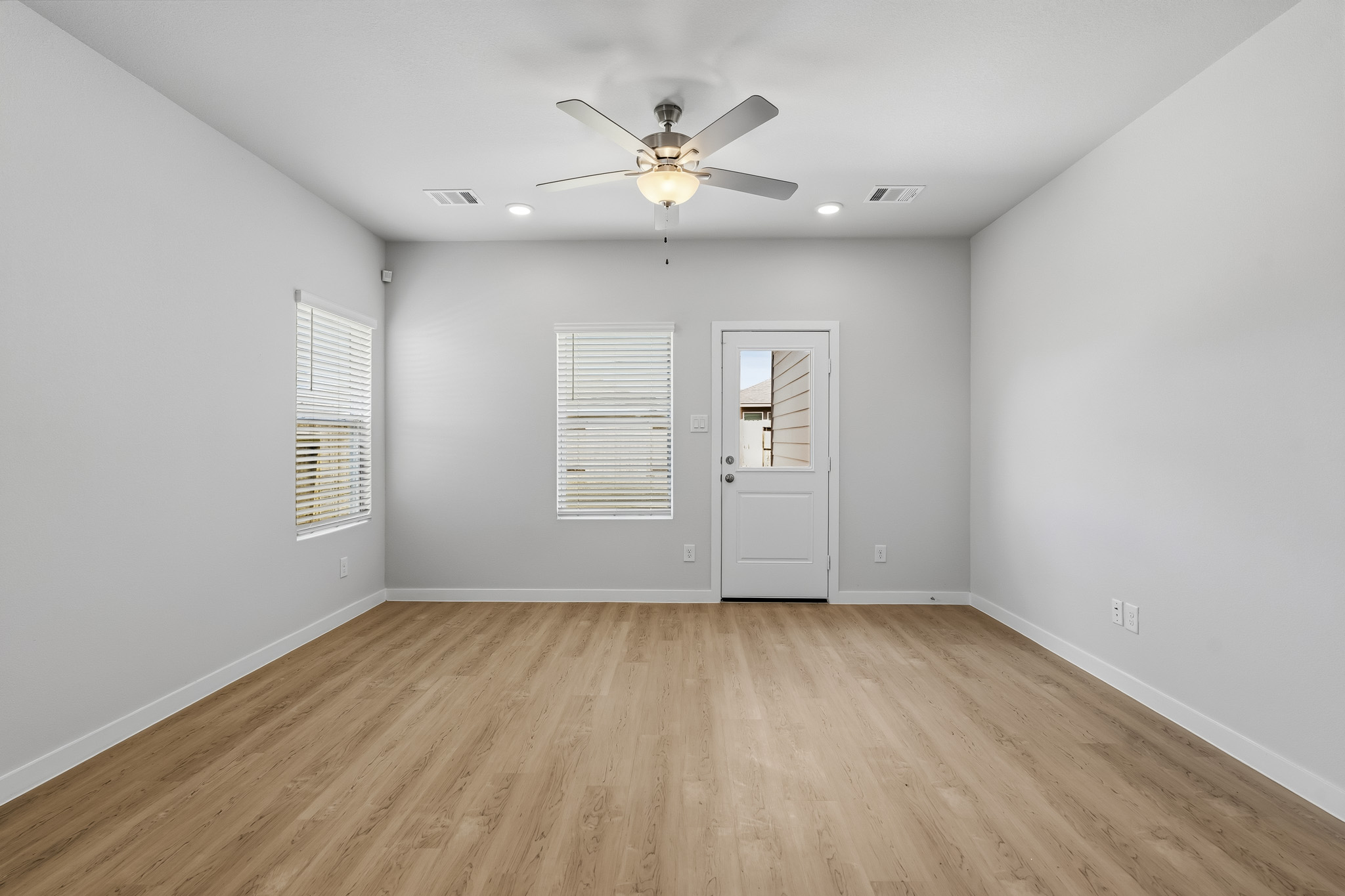 A room with a ceiling fan and a wood floor.